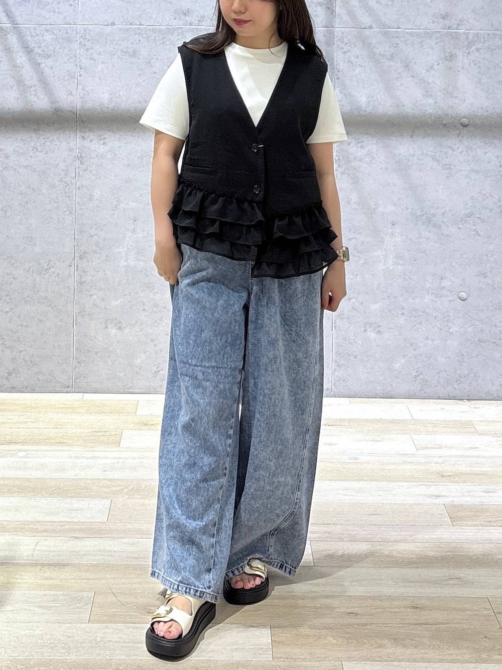ブルー系のデニムパンツ、ホワイト系のサンダル、ホワイト系のTシャツ/カットソーを着用したレディースの春コーディネートの2枚目の写真