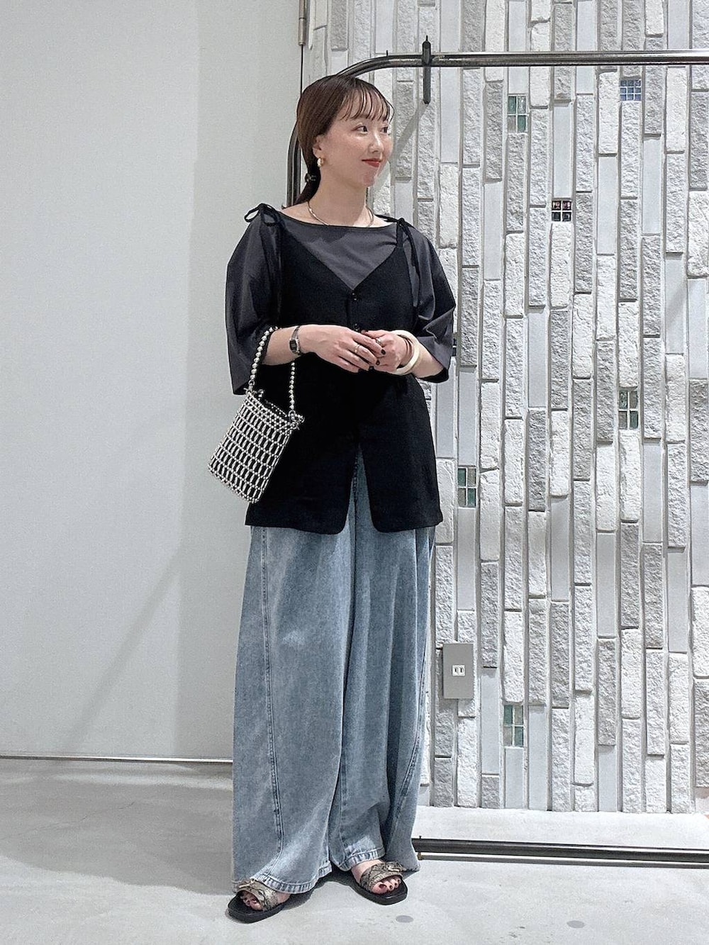 グレー系のTシャツ/カットソー、ブルー系のデニムパンツ、シルバー系のショルダーバッグを着用したレディースの夏コーディネートの2枚目の写真