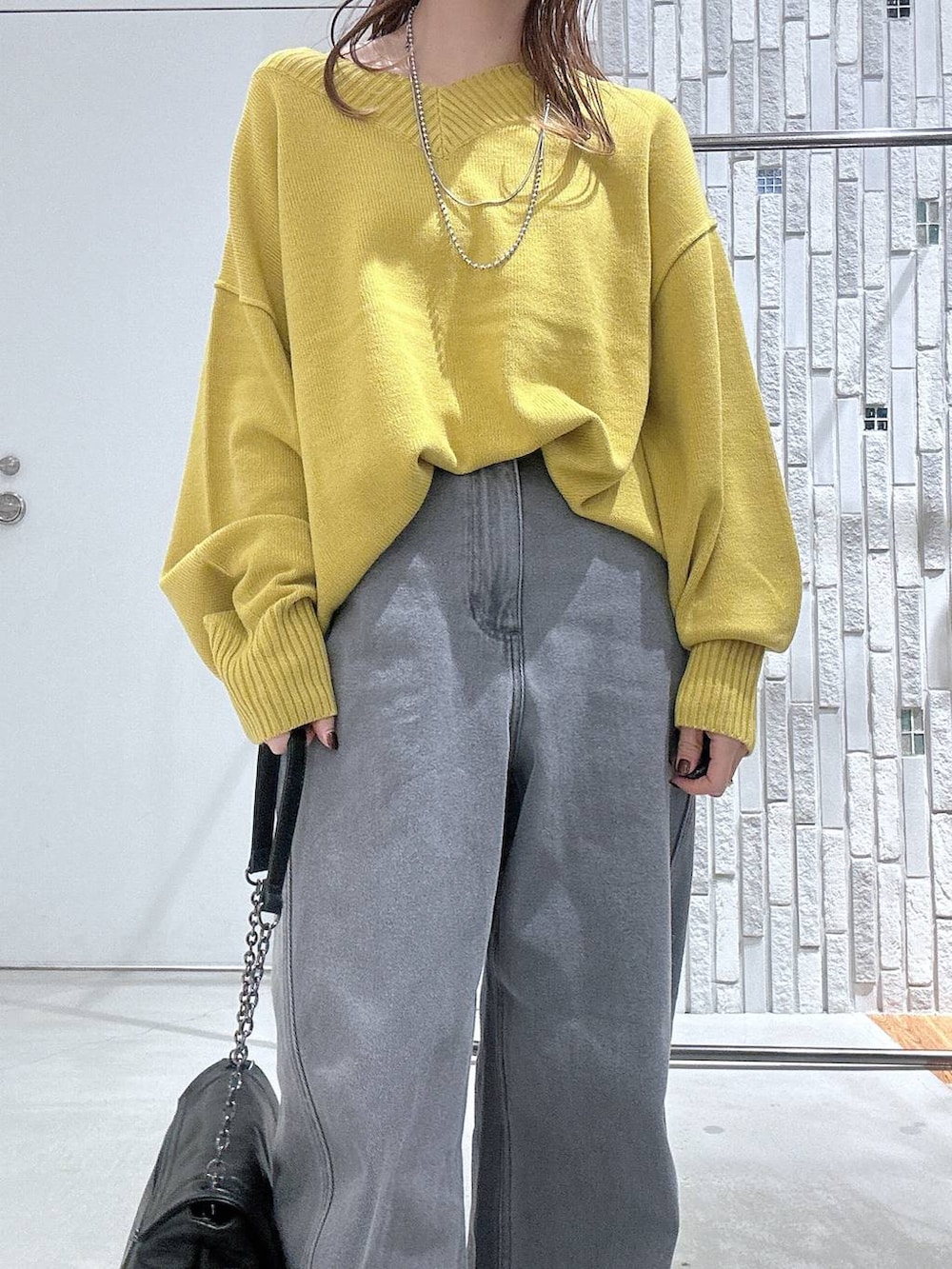 イエロー系のニット/セーター、ブラック系のブーツ、ブラック系のショルダーバッグを着用したレディースの冬コーディネートの4枚目の写真