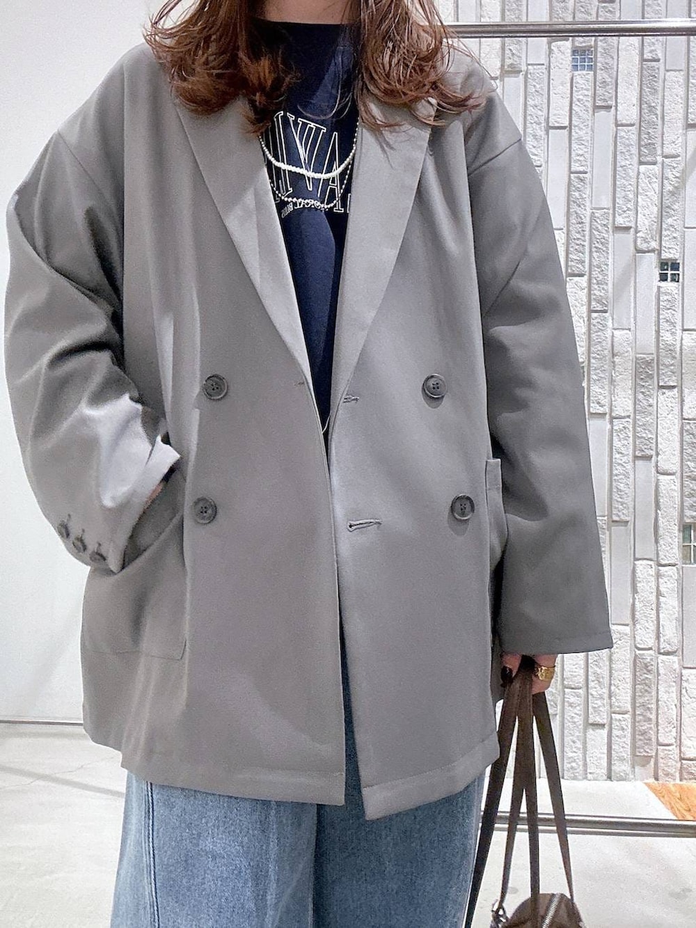 ブラウン系のボストンバッグ、ブルー系のデニムパンツ、グレー系のテーラードジャケットを着用したレディースの冬コーディネートの5枚目の写真