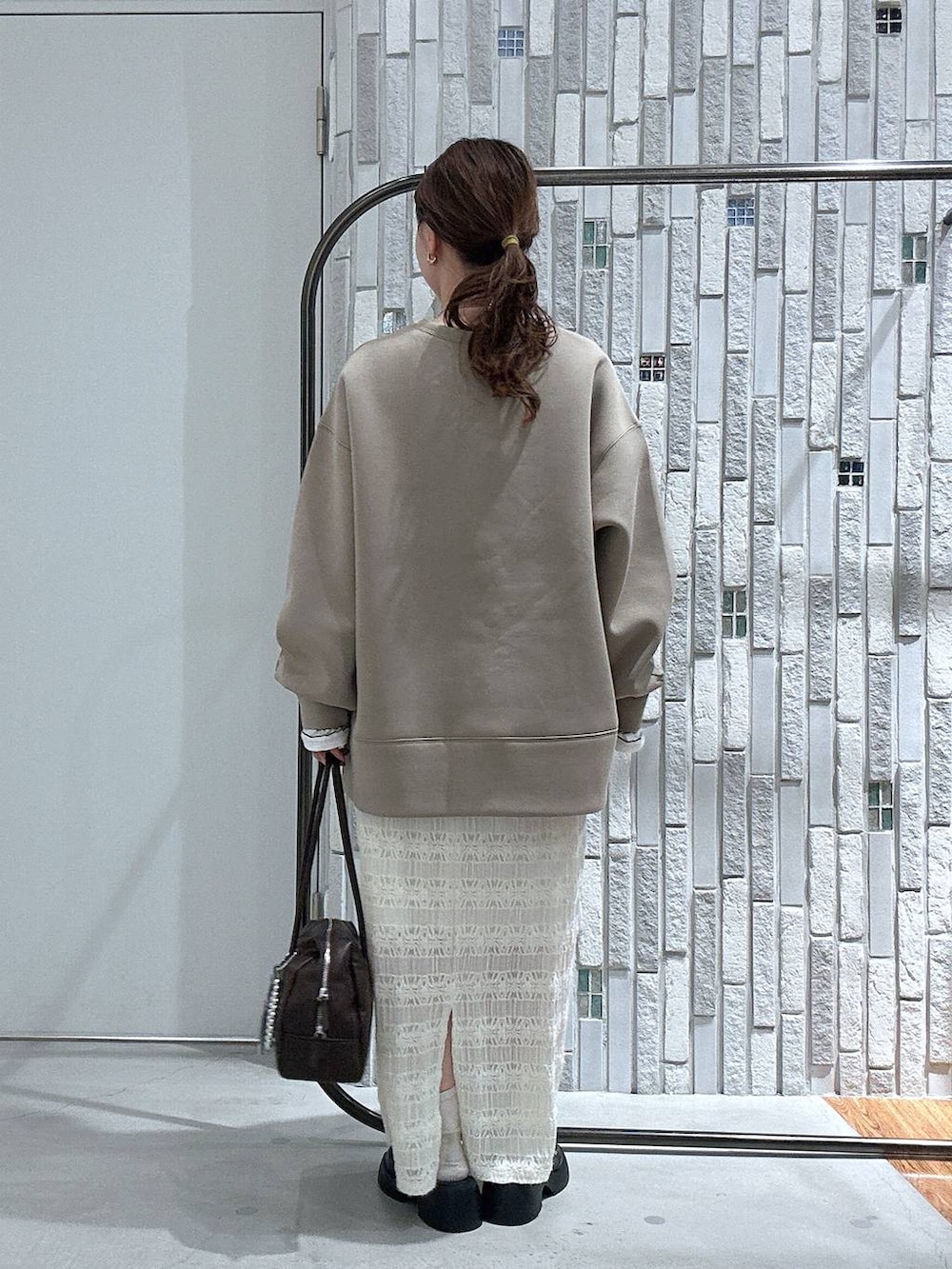 ブラック系のサンダル、ブラウン系のボストンバッグ、ブラウン系のスウェットを着用したレディースの冬コーディネートの4枚目の写真