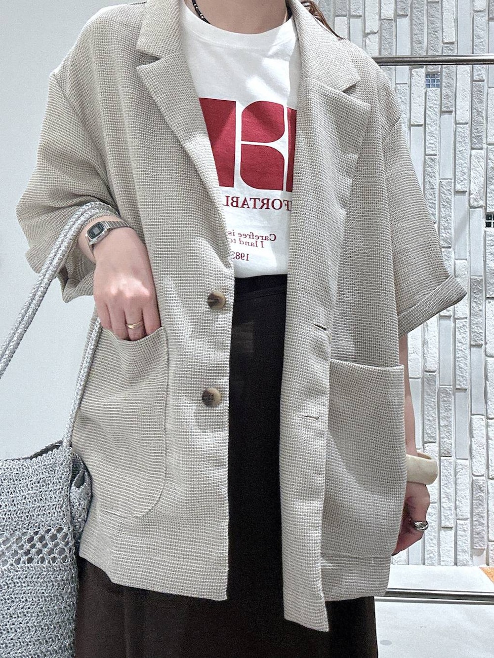 ブラウン系のスカート、ホワイト系のTシャツ/カットソー、ベージュ系のテーラードジャケットを着用したレディースの夏コーディネートの5枚目の写真