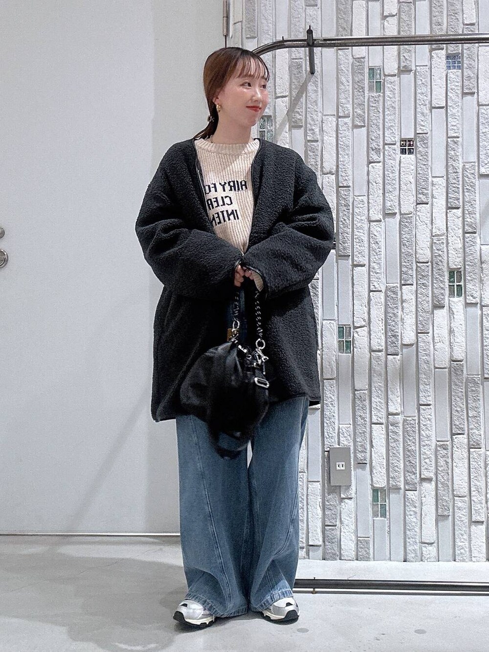 ブラック系のショルダーバッグ、グレー系のその他アウター、ブルー系のデニムパンツを着用したレディースの冬コーディネートの2枚目の写真