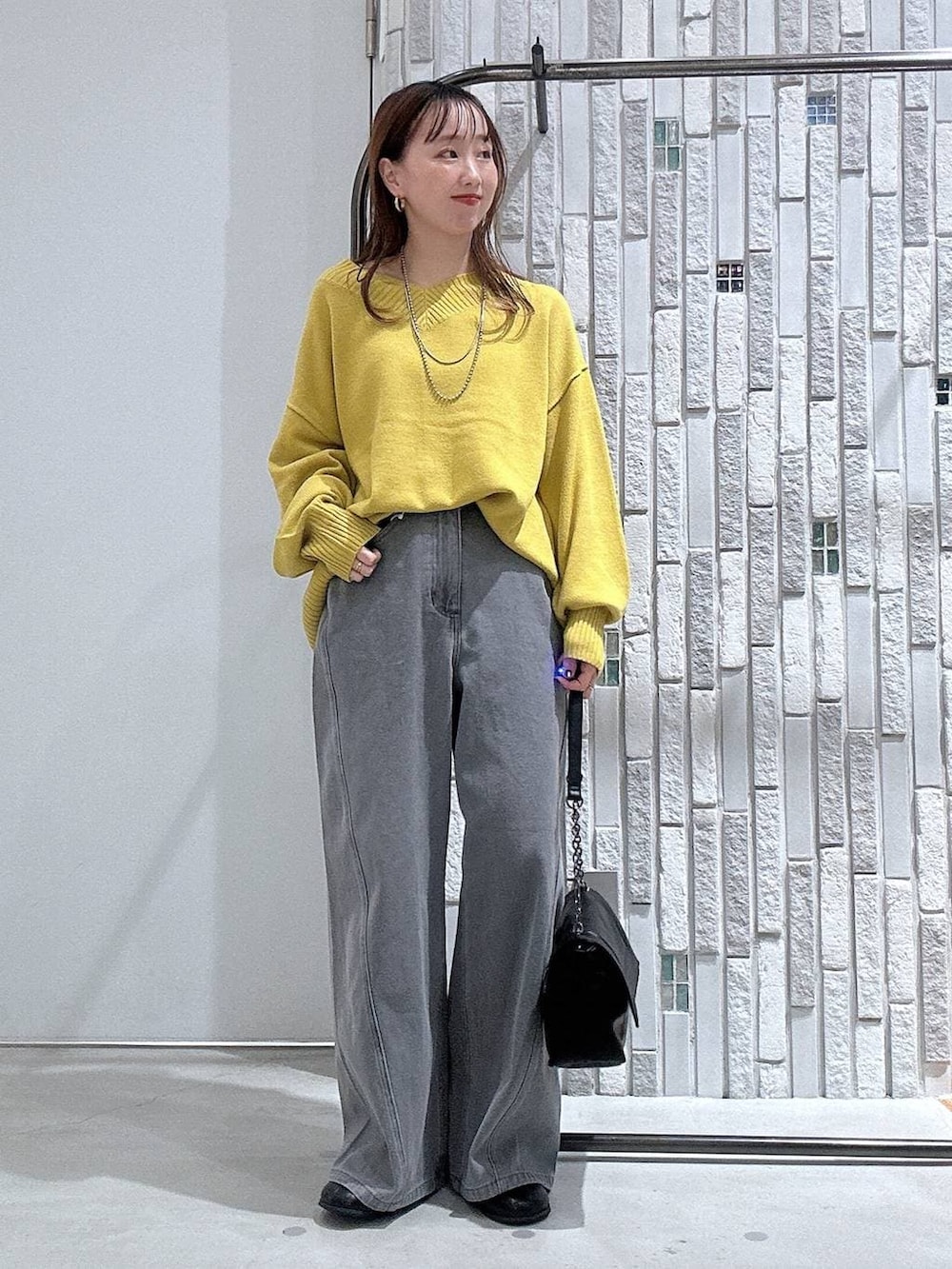 イエロー系のニット/セーター、ブラック系のブーツ、ブラック系のショルダーバッグを着用したレディースの冬コーディネートの2枚目の写真