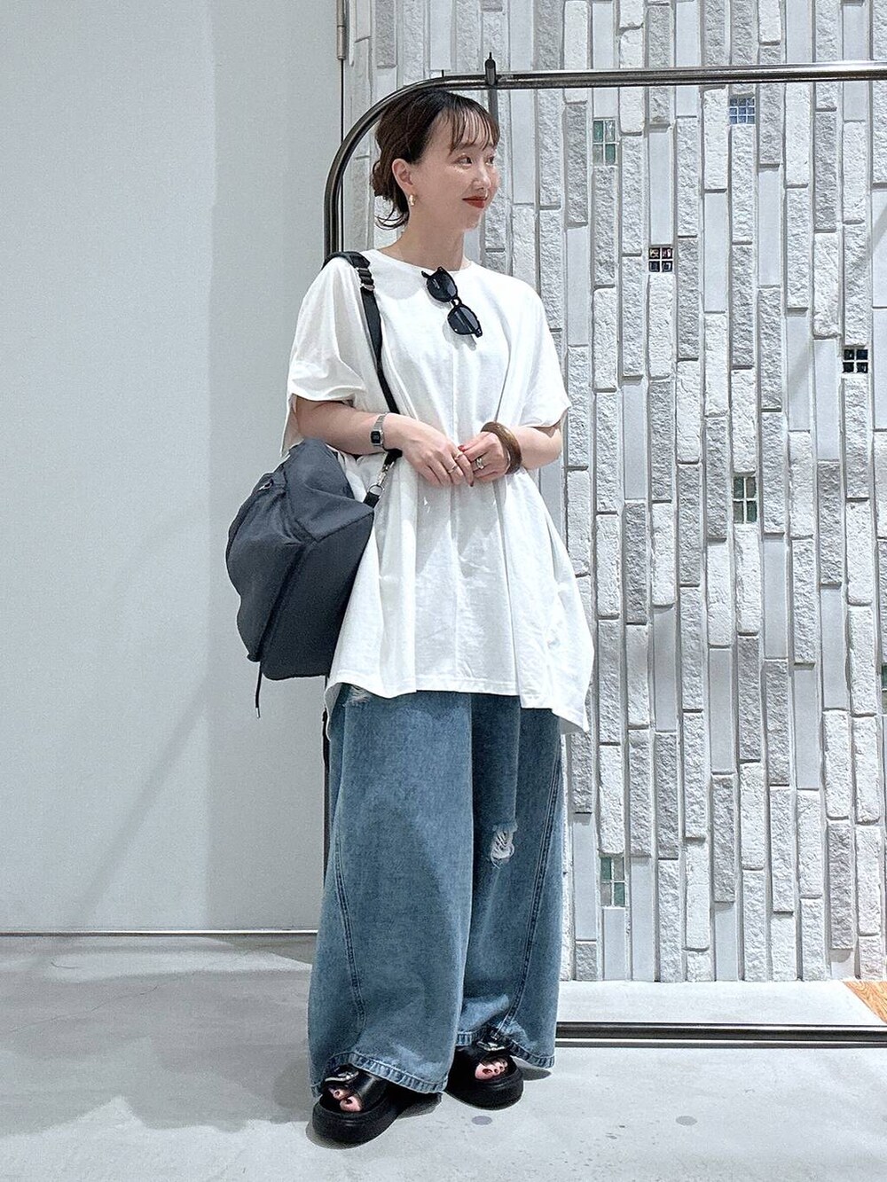 ブルー系のデニムパンツ、ブラック系のサンダル、グレー系のバックパック/リュックを着用したレディースの春コーディネートの2枚目の写真