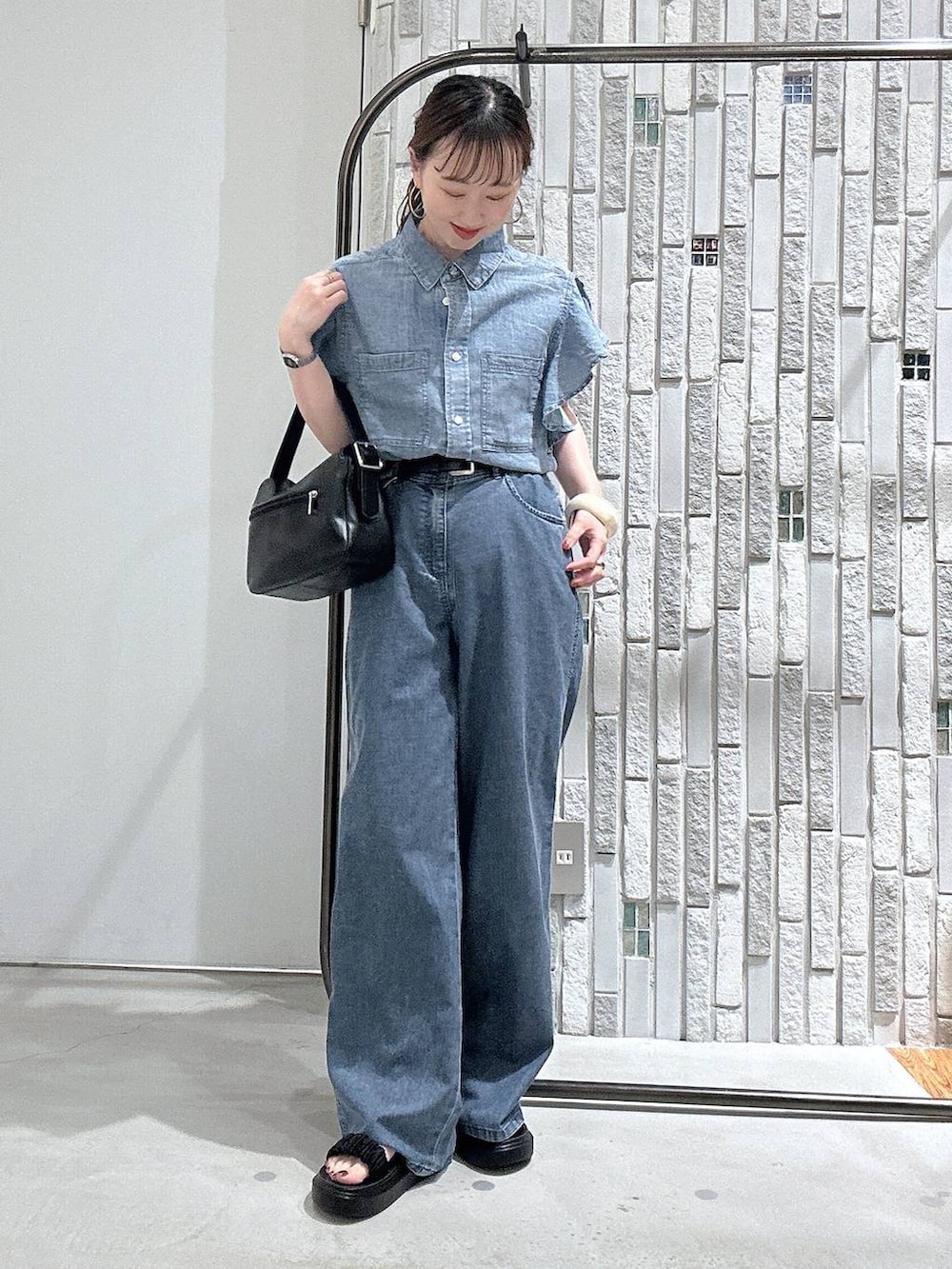 ブルー系のデニムパンツ、ブラック系のサンダル、ブラック系のショルダーバッグを着用したレディースの春コーディネートの2枚目の写真
