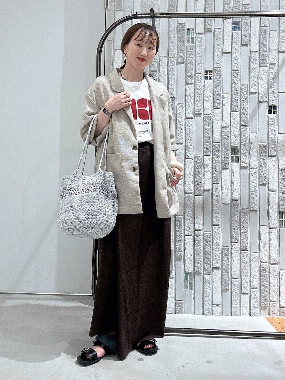 ブラウン系のスカート、ホワイト系のTシャツ/カットソー、ベージュ系のテーラードジャケットを着用したレディースの夏コーディネートの2枚目の写真
