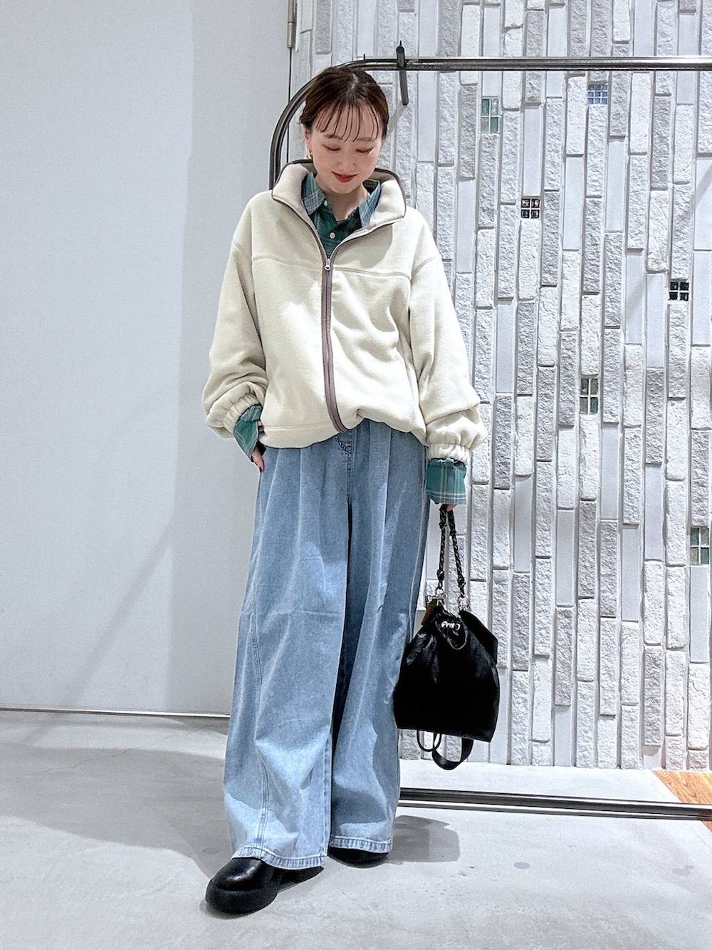 ブラック系のショルダーバッグ、ブラック系のサンダル、ブルー系のデニムパンツを着用したレディースの冬コーディネートの2枚目の写真