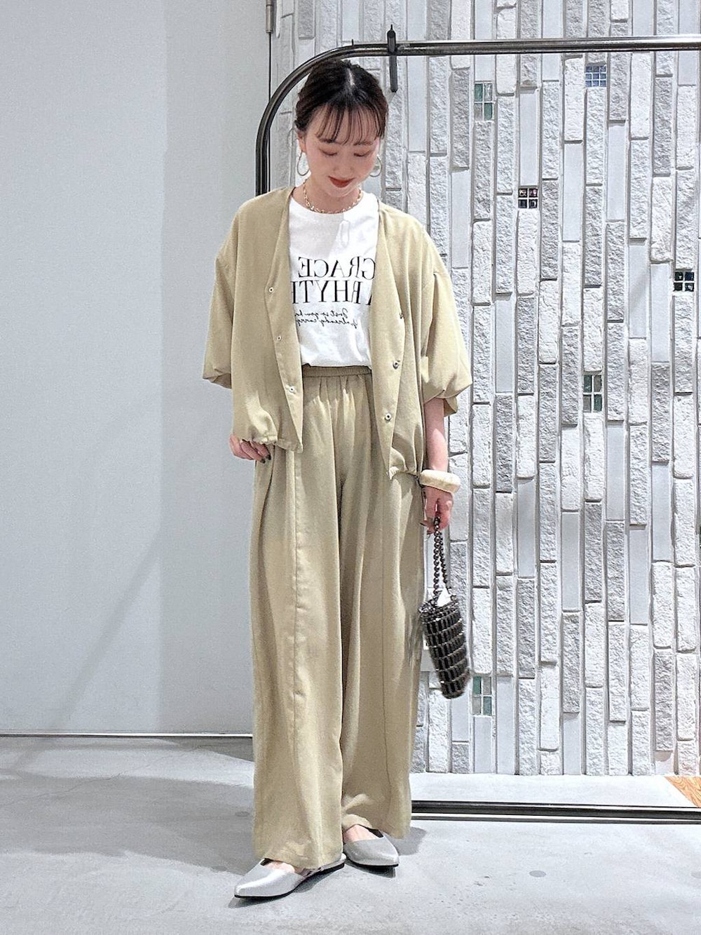 ベージュ系のその他パンツ、ベージュ系のシャツ/ブラウス、シルバー系のショルダーバッグを着用したレディースの春コーディネートの2枚目の写真