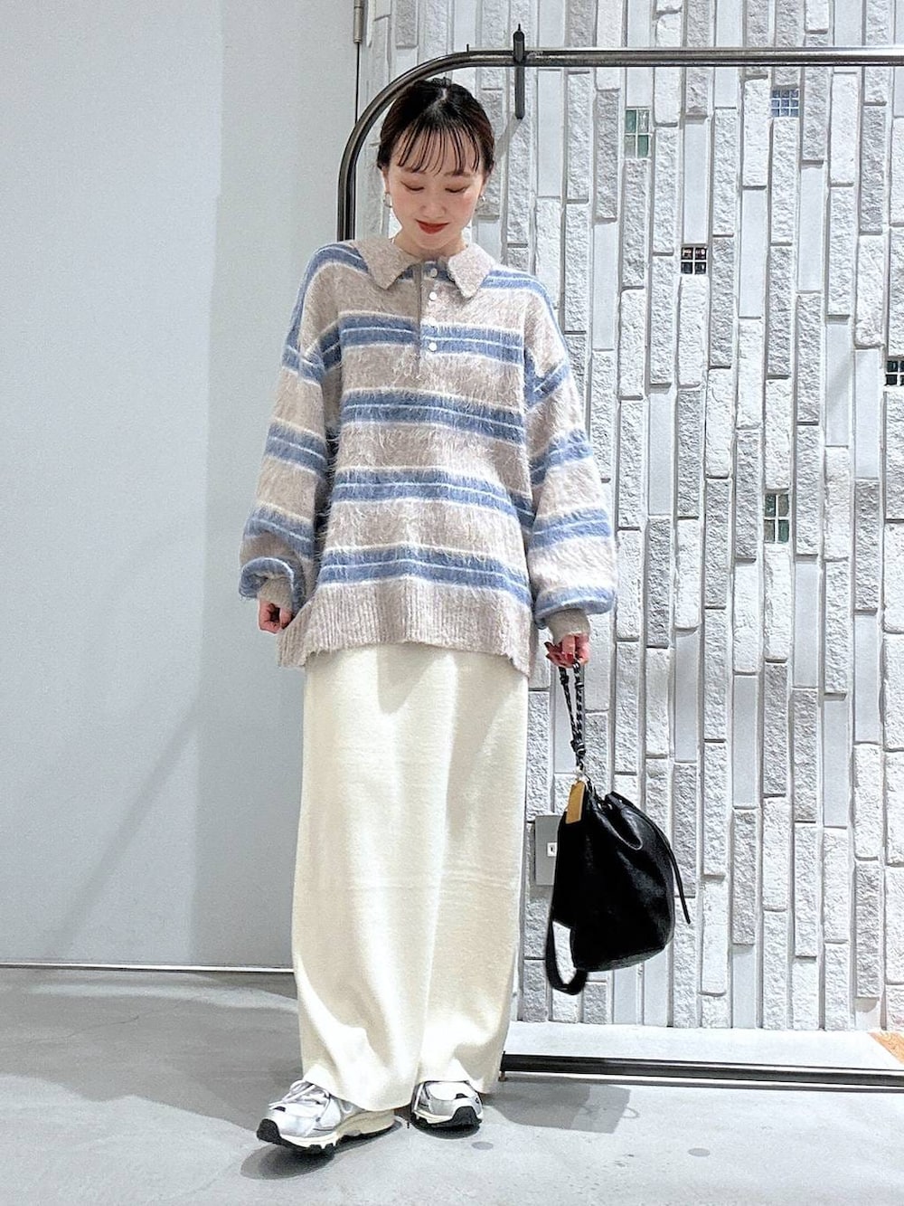 ブラック系のショルダーバッグ、ホワイト系のスカート、ブラック系のブルゾンを着用したレディースの冬コーディネートの6枚目の写真