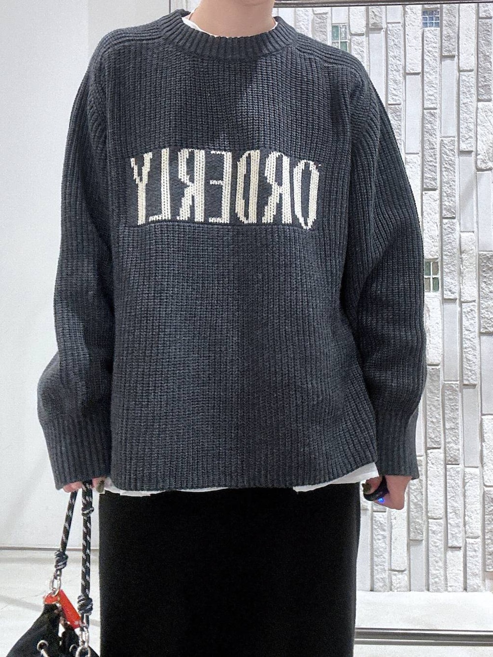 ブラック系のショルダーバッグ、ブラック系のスカート、ホワイト系のTシャツ/カットソーを着用したレディースの冬コーディネートの6枚目の写真