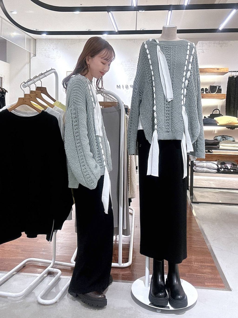 ブラック系のスカート、ブラウン系のブーツ、グリーン系のニット/セーターを着用したレディースの冬コーディネートの3枚目の写真