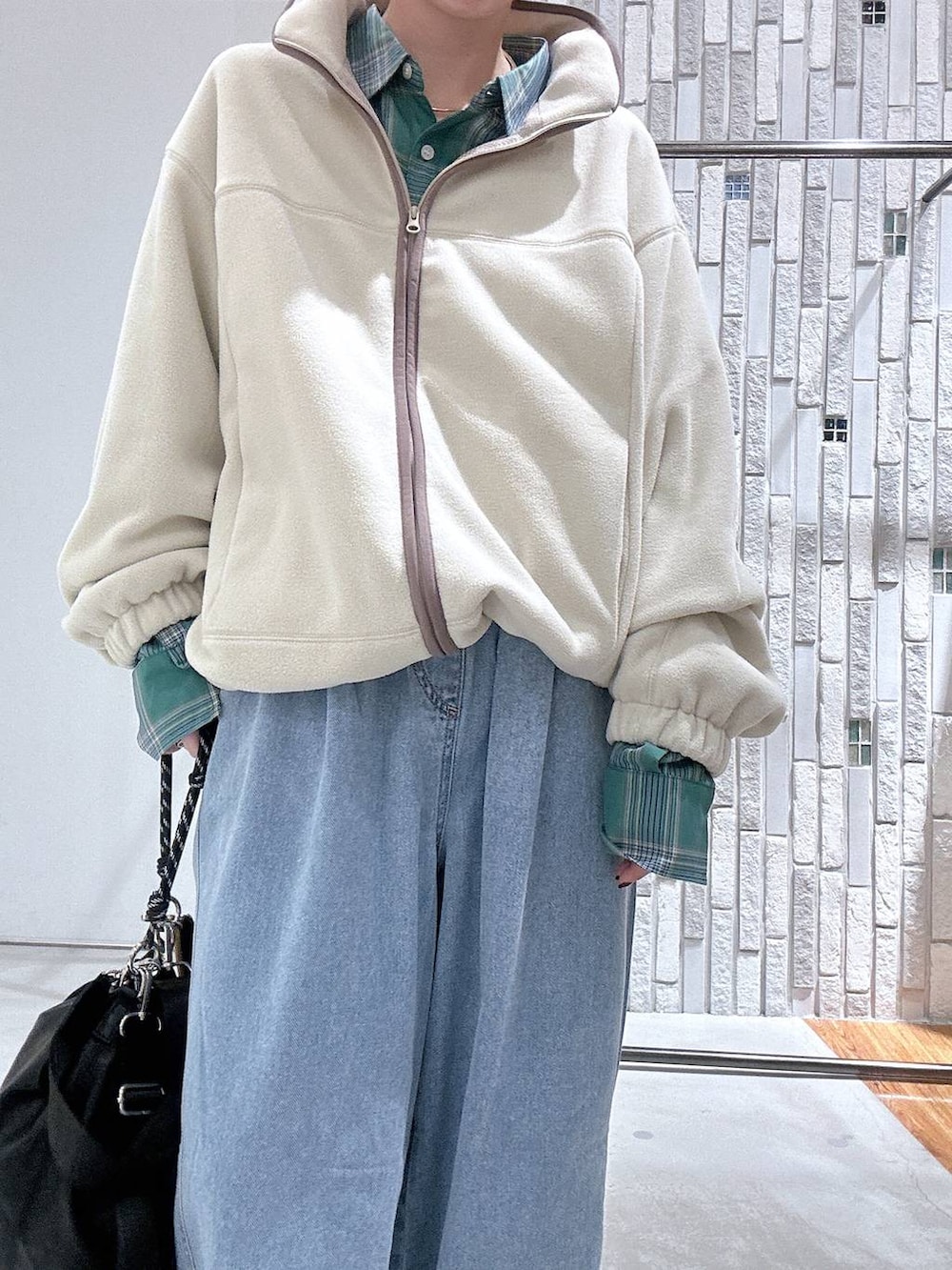 ブラック系のショルダーバッグ、ブラック系のサンダル、ブルー系のデニムパンツを着用したレディースの冬コーディネートの5枚目の写真