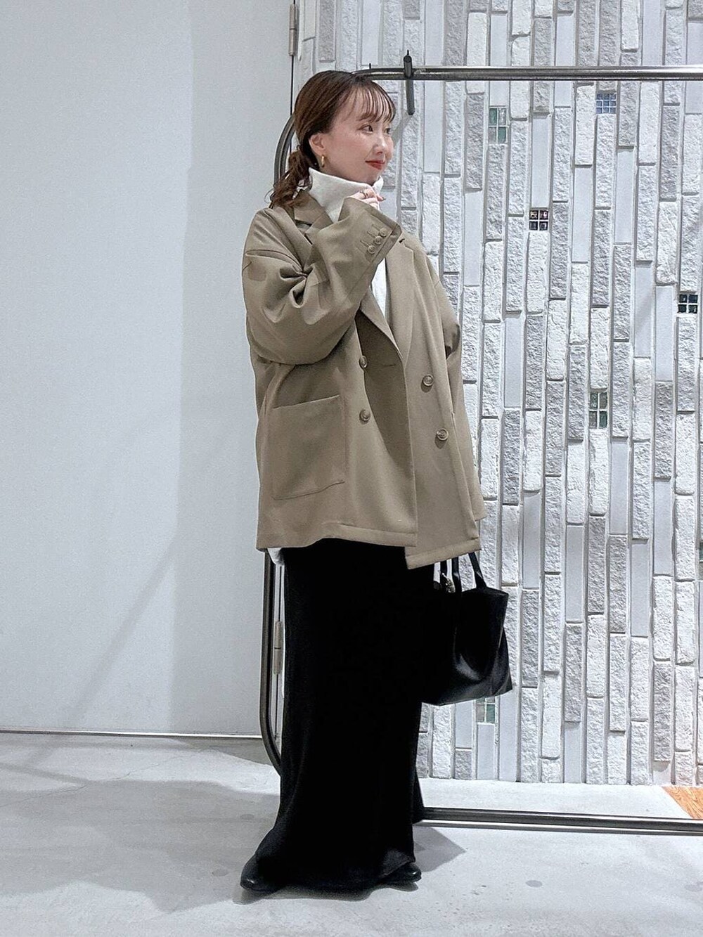 ブラック系のスカート、ブラウン系のテーラードジャケット、ブラック系のトートバッグを着用したレディースの冬コーディネートの2枚目の写真