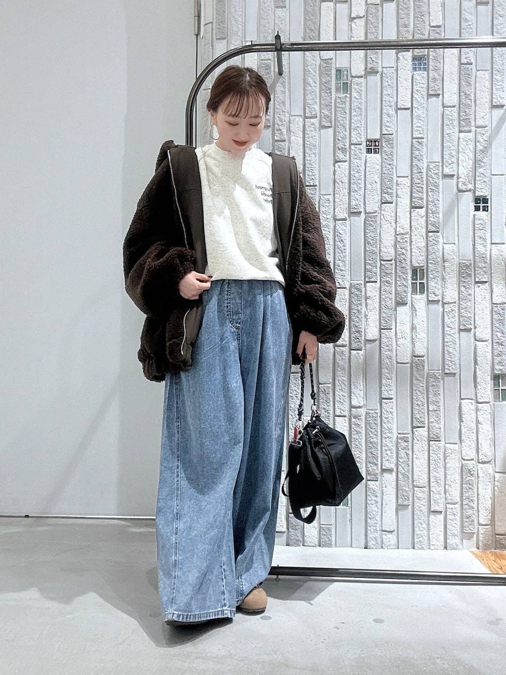 ブラック系のショルダーバッグ、ブルー系のデニムパンツ、ブラウン系のブルゾンを着用したレディースの冬コーディネートの2枚目の写真