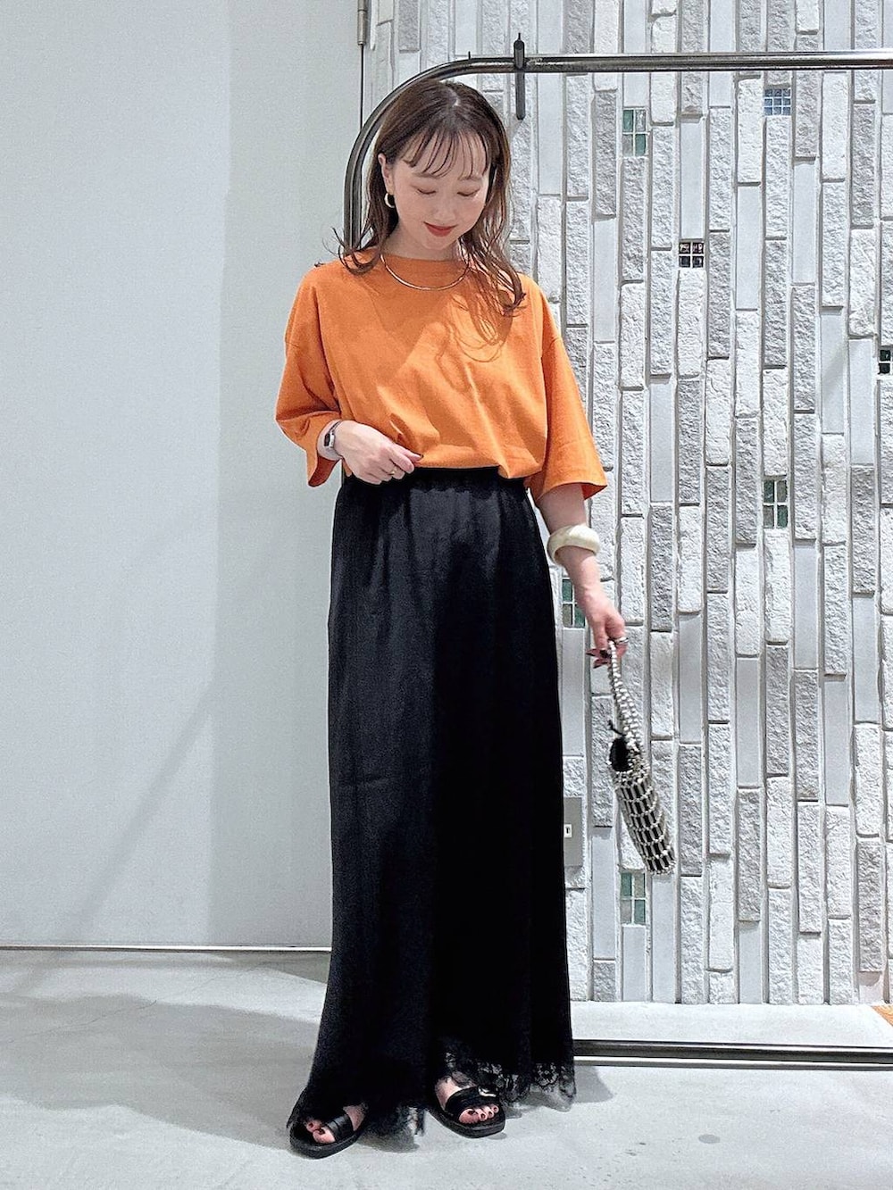 オレンジ系のTシャツ/カットソー、ベージュ系のシャツ/ブラウス、シルバー系のショルダーバッグを着用したレディースの夏コーディネートの6枚目の写真
