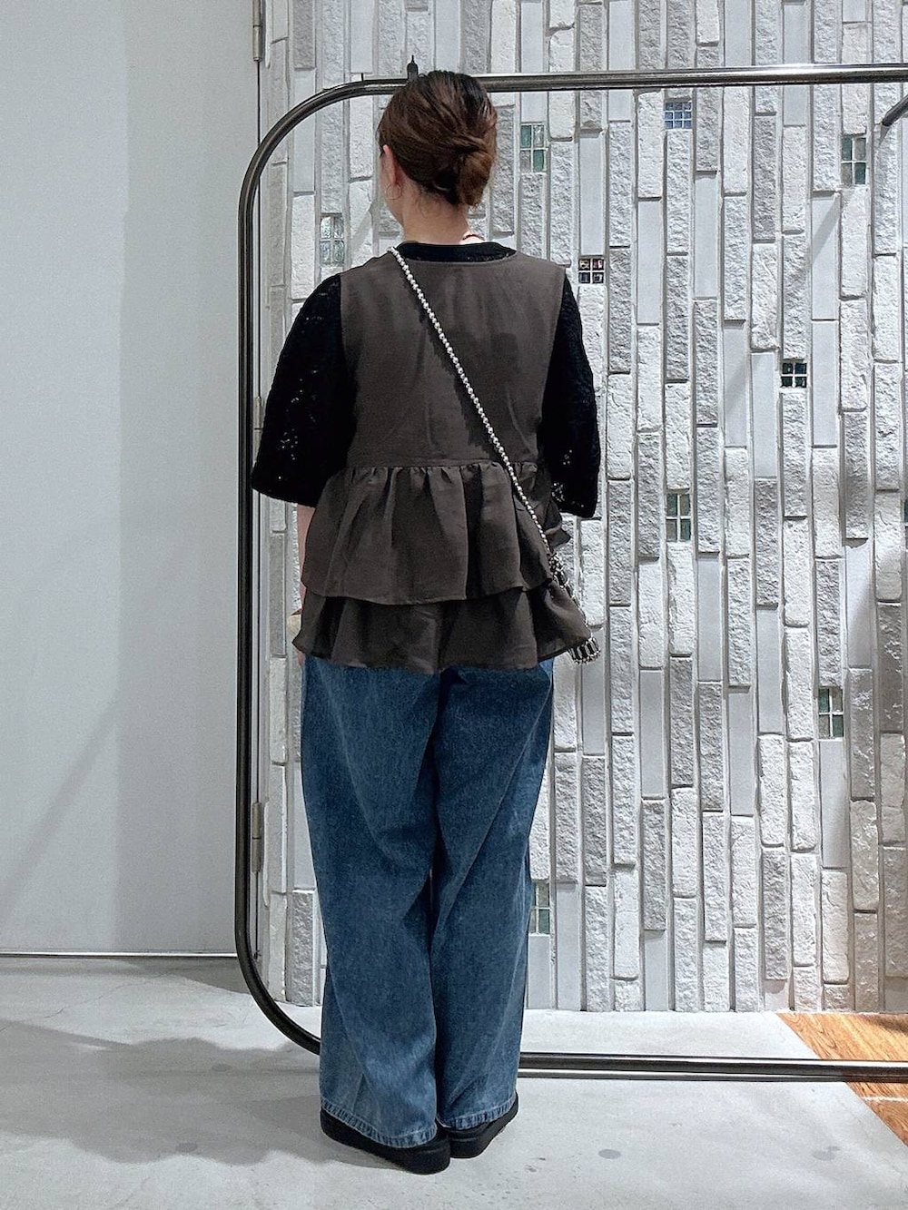 ブルー系のデニムパンツ、ブラック系のサンダル、シルバー系のショルダーバッグを着用したレディースの夏コーディネートの3枚目の写真