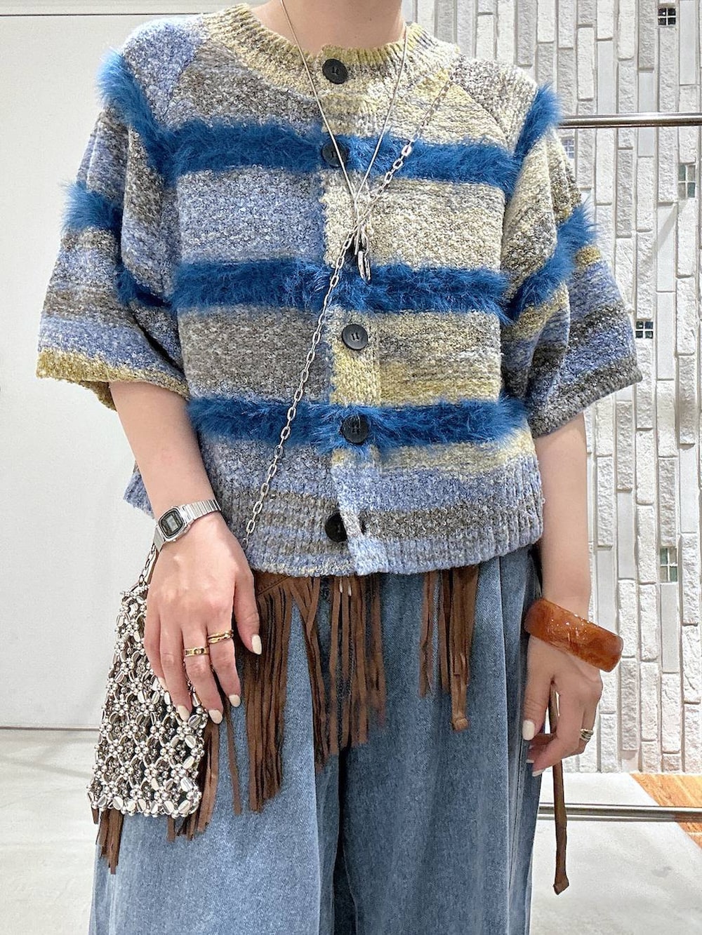 ブルー系のニット/セーター、ブラウン系のサンダル、ブルー系のデニムパンツを着用したレディースの夏コーディネートの4枚目の写真
