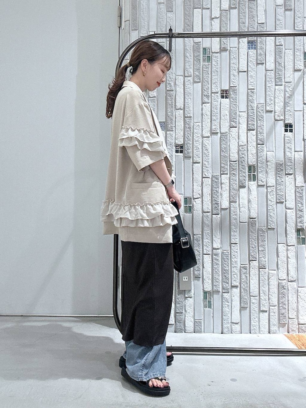 ブルー系のデニムパンツ、ブラック系のサンダル、ブラック系のショルダーバッグを着用したレディースの春コーディネートの4枚目の写真
