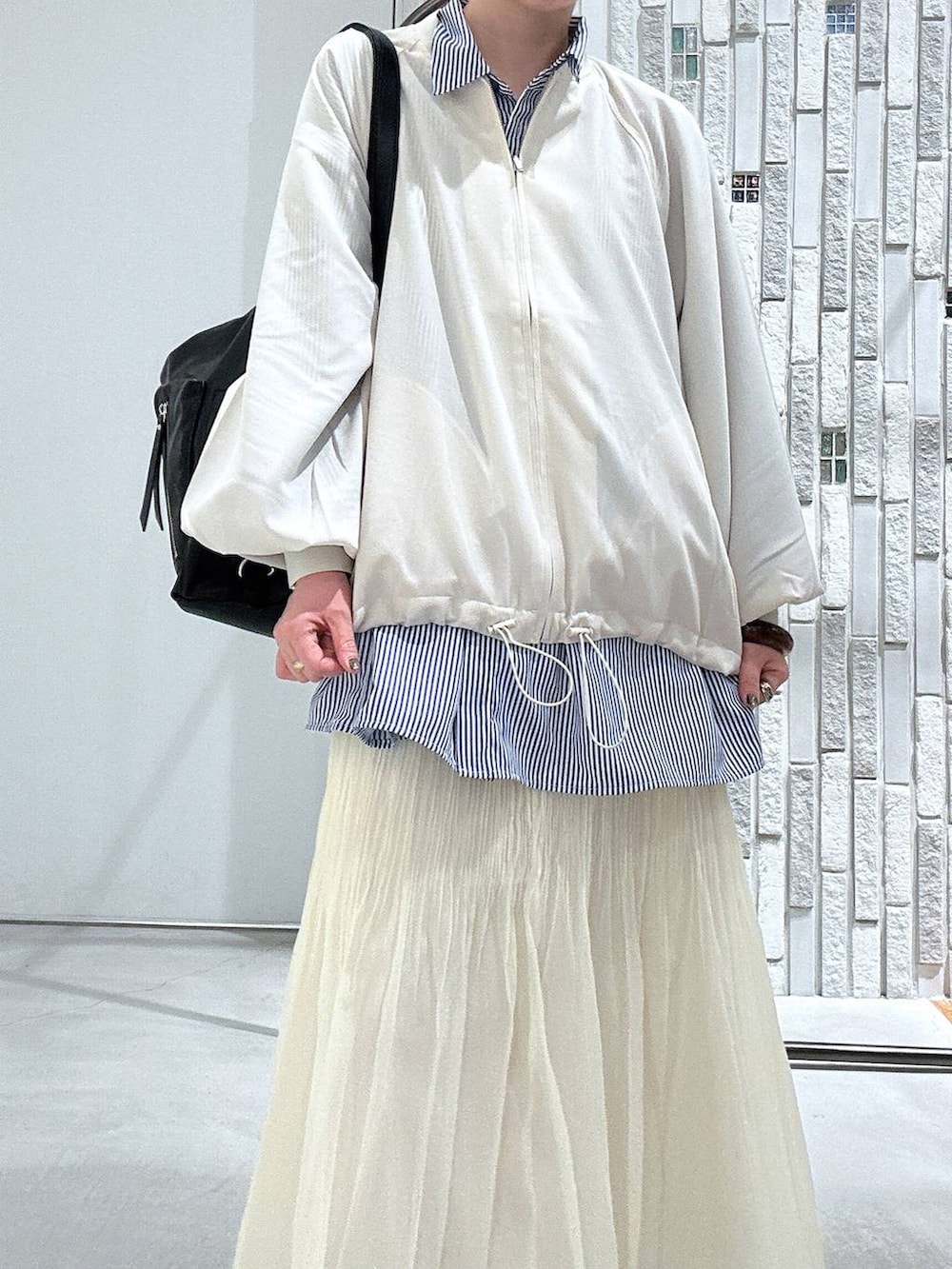 ブラック系のショルダーバッグ、ブルー系のシャツ/ブラウス、ホワイト系のブルゾンを着用したレディースの春コーディネートの6枚目の写真