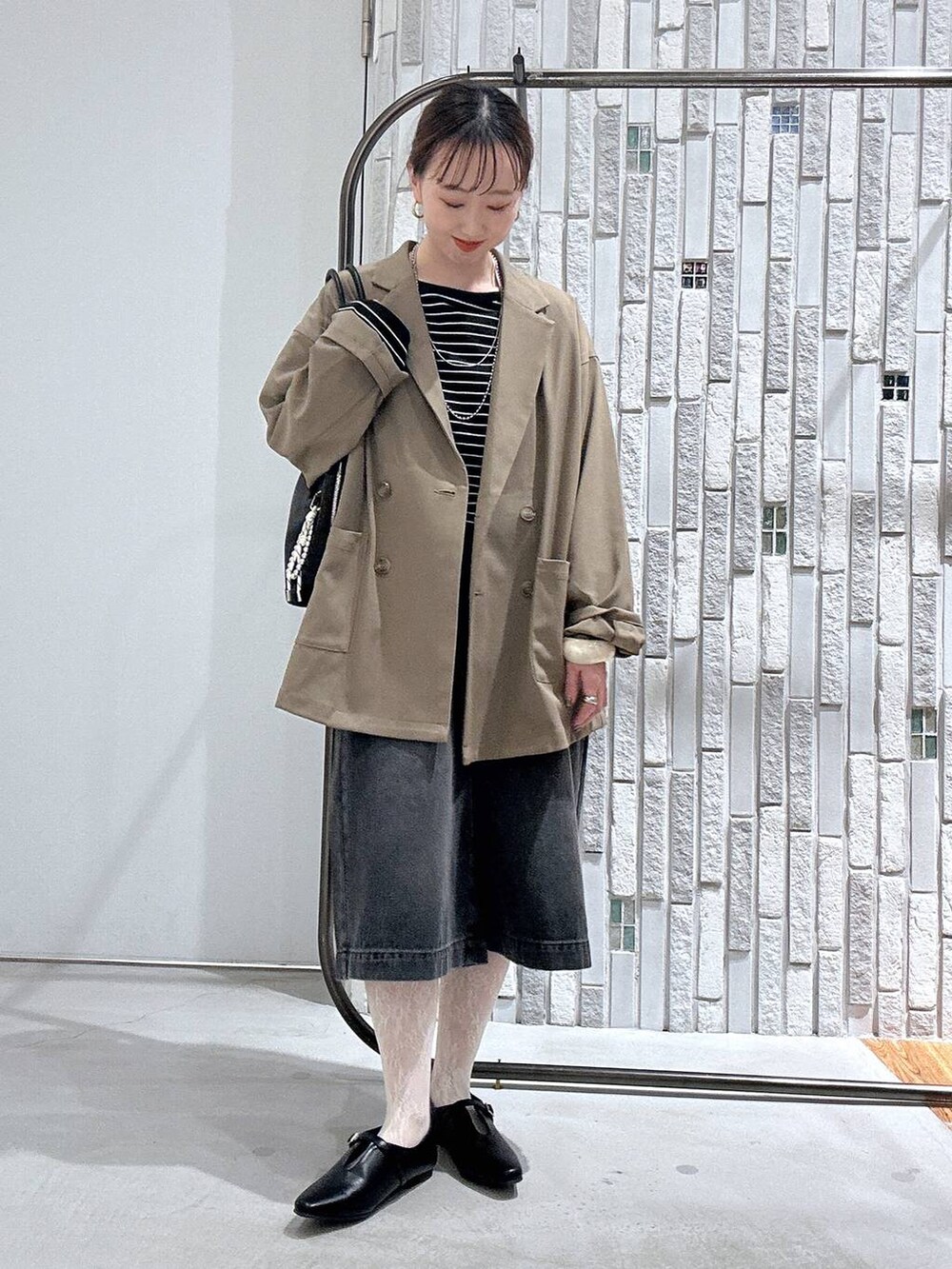 ブラウン系のテーラードジャケット、ブラック系のボストンバッグ、ブラック系のTシャツ/カットソーを着用したレディースの春コーディネートの3枚目の写真