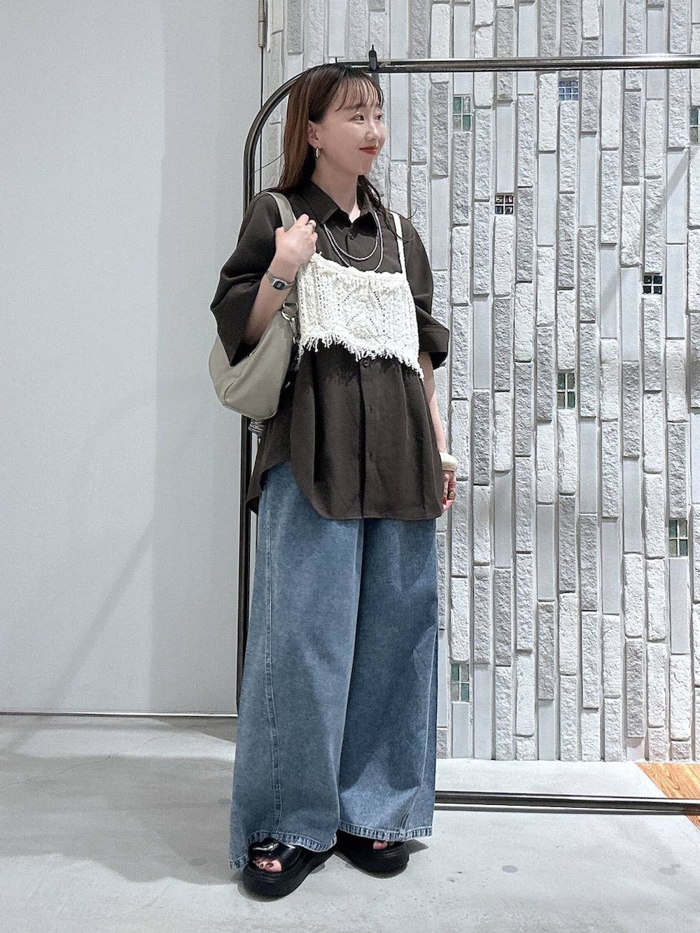 ブルー系のデニムパンツ、ブラック系のサンダル、ベージュ系のショルダーバッグを着用したレディースの春コーディネートの2枚目の写真