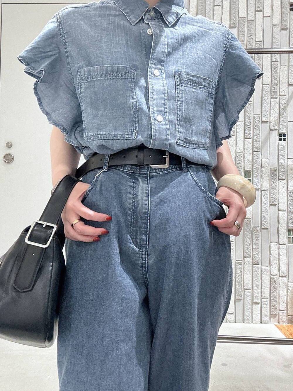 ブルー系のデニムパンツ、ブラック系のサンダル、ブラック系のショルダーバッグを着用したレディースの春コーディネートの5枚目の写真