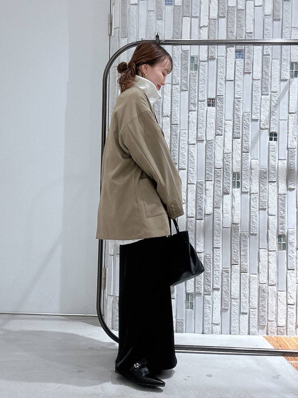 ブラック系のスカート、ブラウン系のテーラードジャケット、ブラック系のトートバッグを着用したレディースの冬コーディネートの3枚目の写真