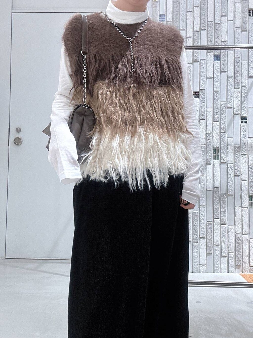 ホワイト系のTシャツ/カットソー、ブラック系のブーツ、ブラック系のスカートを着用したレディースの冬コーディネートの6枚目の写真