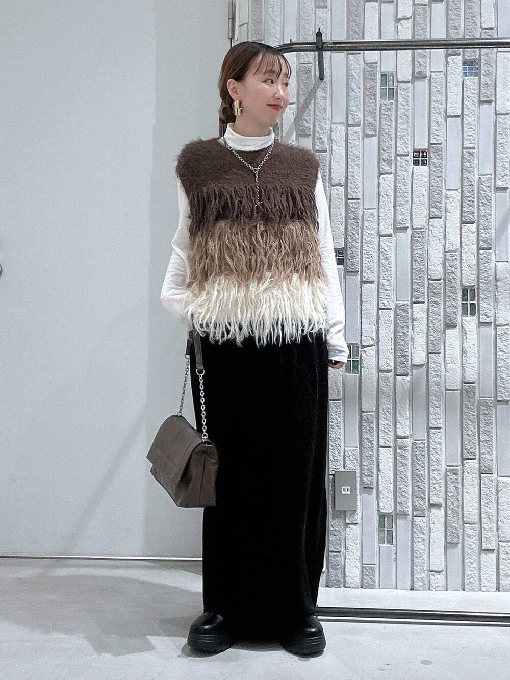 ホワイト系のTシャツ/カットソー、ブラック系のブーツ、ブラック系のスカートを着用したレディースの冬コーディネートの2枚目の写真