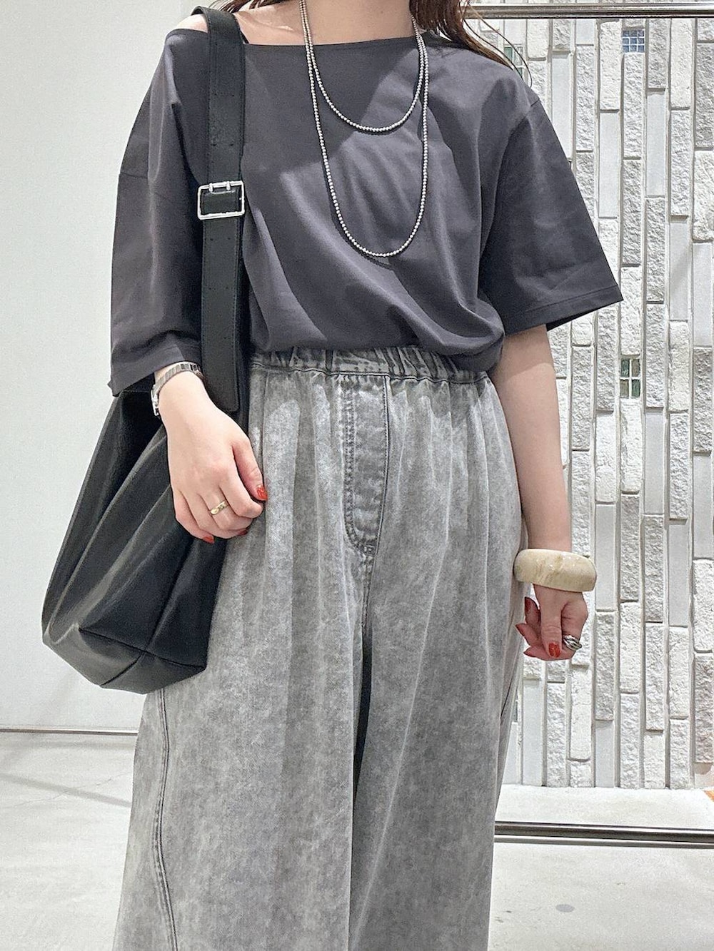 グレー系のTシャツ/カットソー、グレー系のデニムパンツ、ブラック系のサンダルを着用したレディースの春コーディネートの4枚目の写真