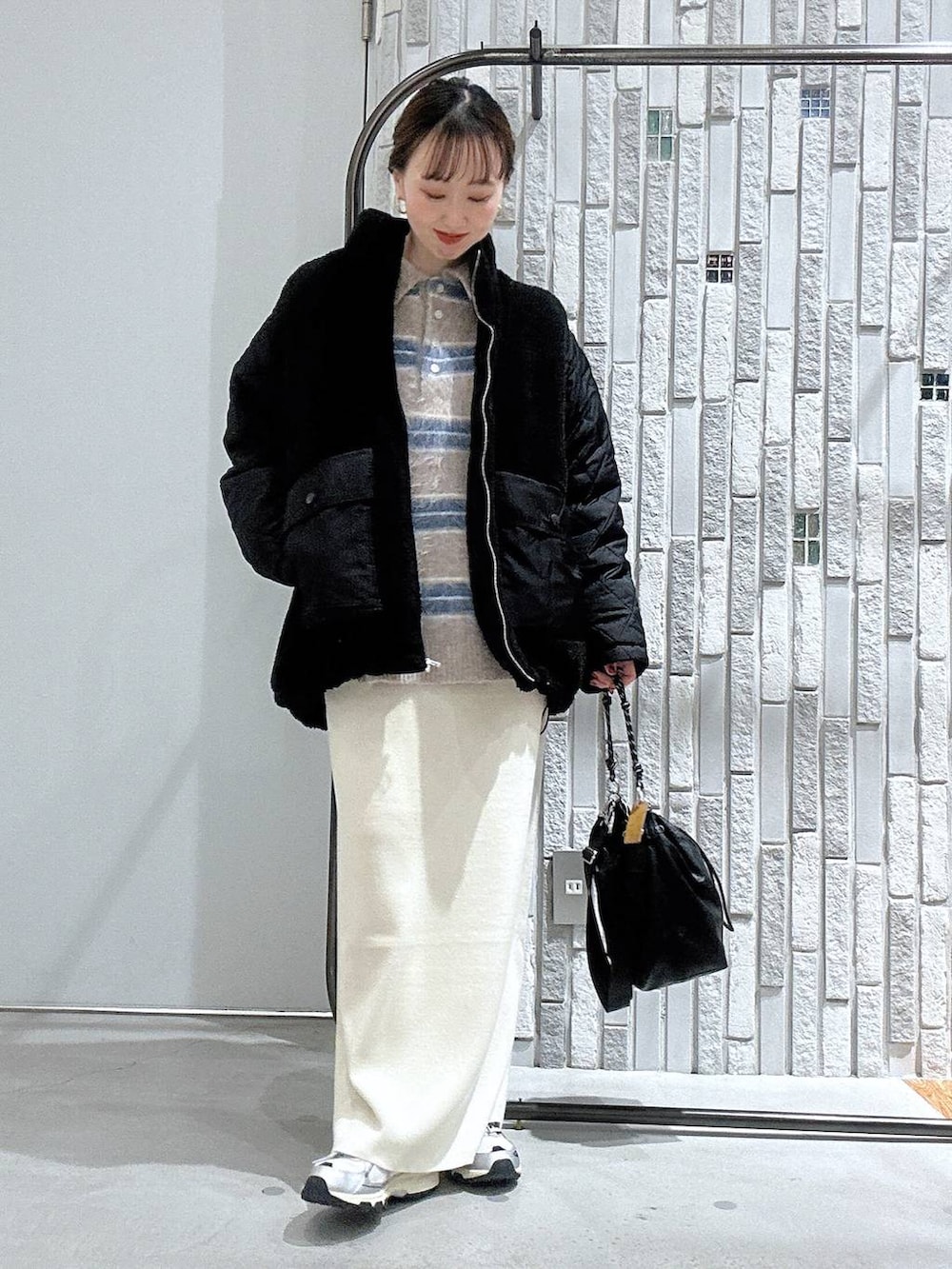 ブラック系のショルダーバッグ、ホワイト系のスカート、ブラック系のブルゾンを着用したレディースの冬コーディネートの2枚目の写真