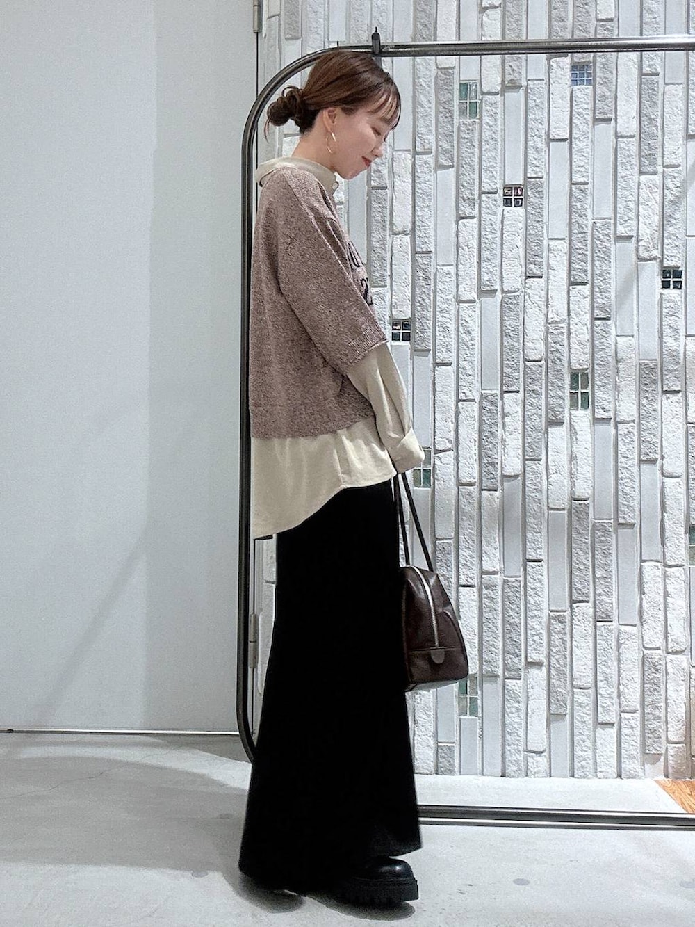 ブラック系のブーツ、ブラック系のスカート、ブラウン系のボストンバッグを着用したレディースの冬コーディネートの3枚目の写真