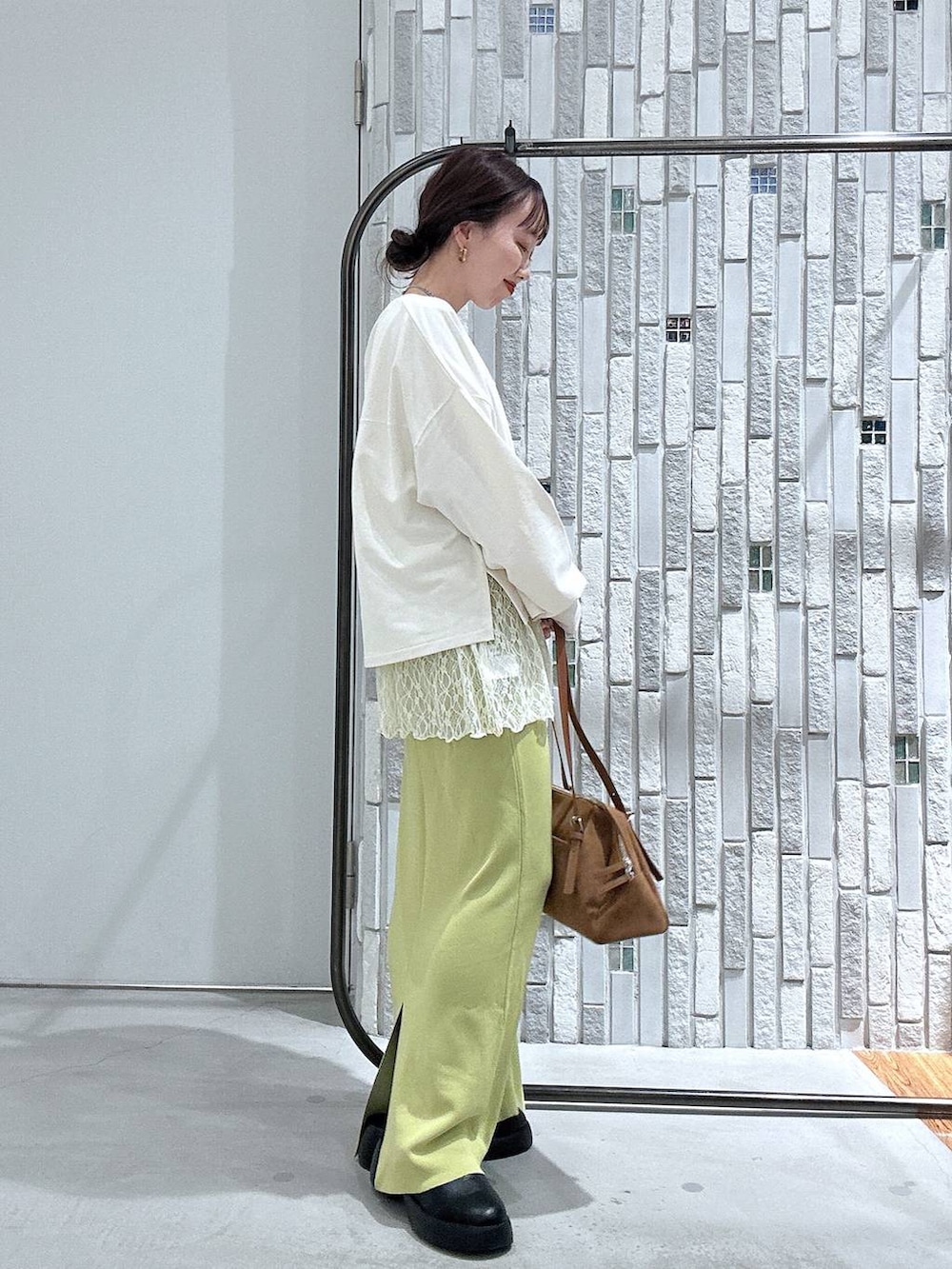 グリーン系のスカート、ブラック系のサンダル、イエロー系のボストンバッグを着用したレディースの春コーディネートの3枚目の写真