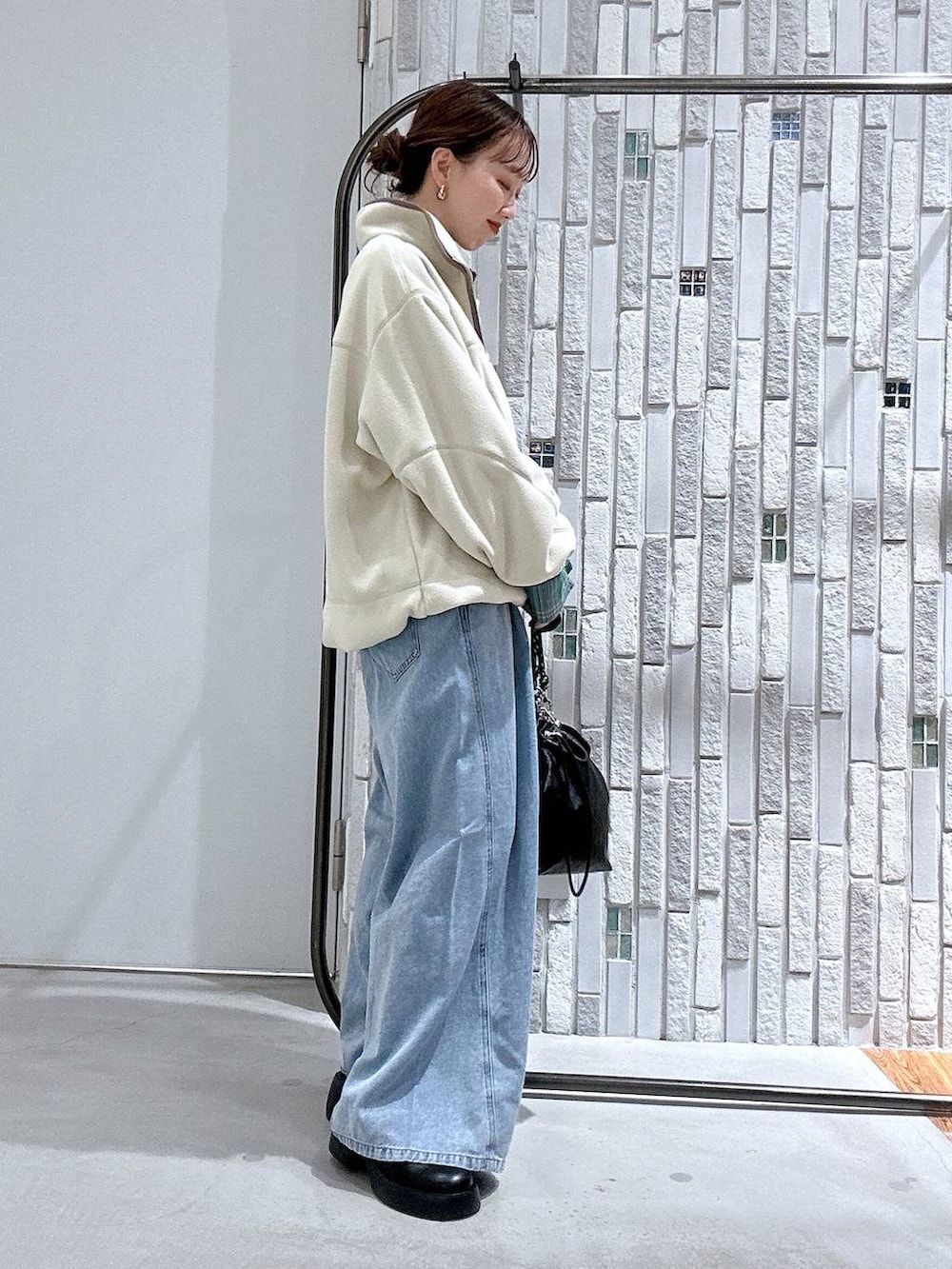 ブラック系のショルダーバッグ、ブラック系のサンダル、ブルー系のデニムパンツを着用したレディースの冬コーディネートの3枚目の写真