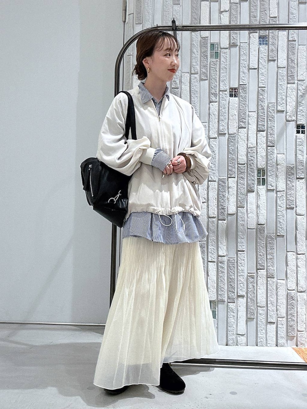 ブラック系のショルダーバッグ、ブルー系のシャツ/ブラウス、ホワイト系のブルゾンを着用したレディースの春コーディネートの2枚目の写真
