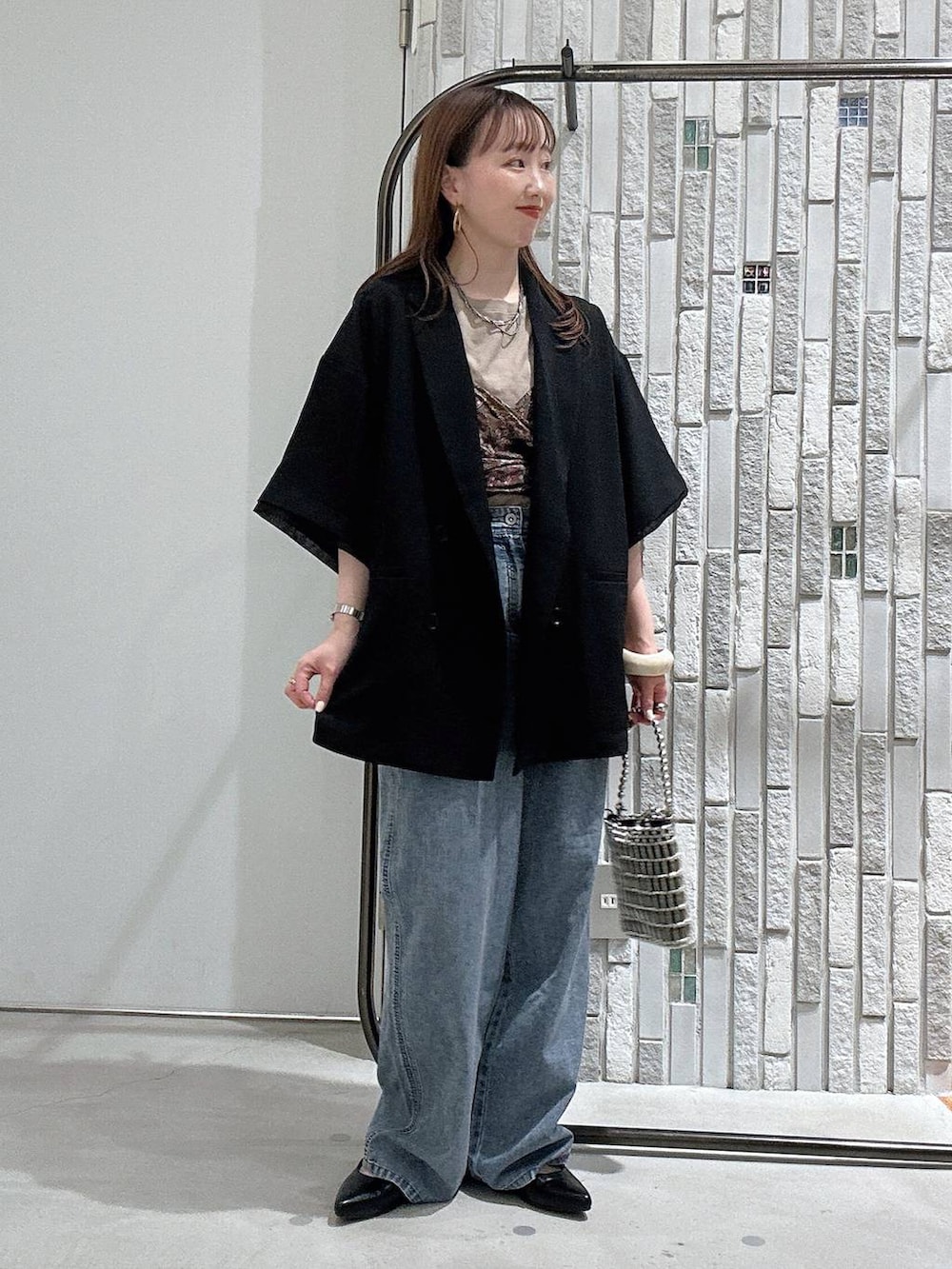 ブルー系のデニムパンツ、ブラック系のテーラードジャケット、シルバー系のショルダーバッグを着用したレディースの春コーディネートの2枚目の写真