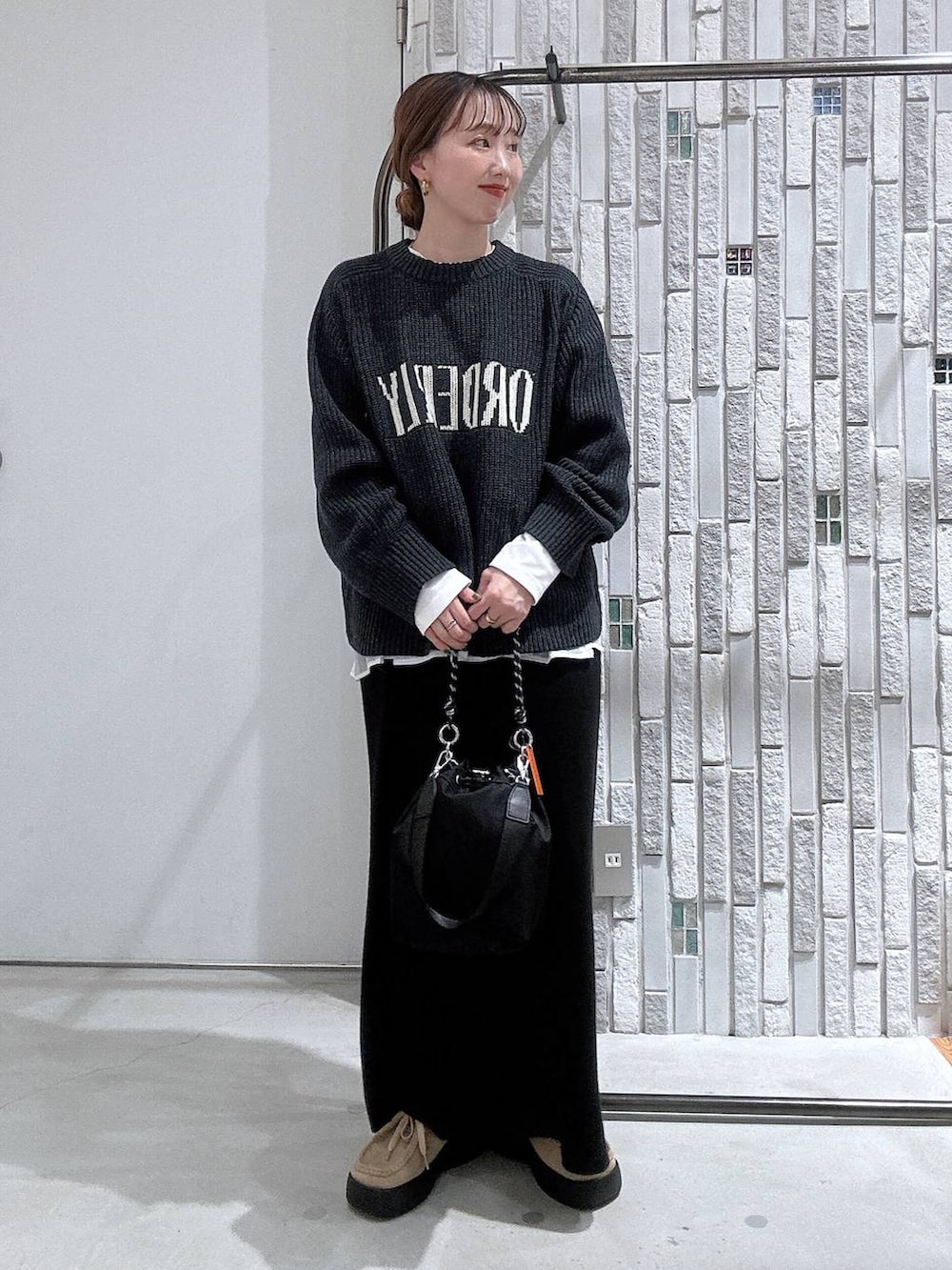 ブラック系のショルダーバッグ、ブラック系のスカート、ホワイト系のTシャツ/カットソーを着用したレディースの冬コーディネートの3枚目の写真