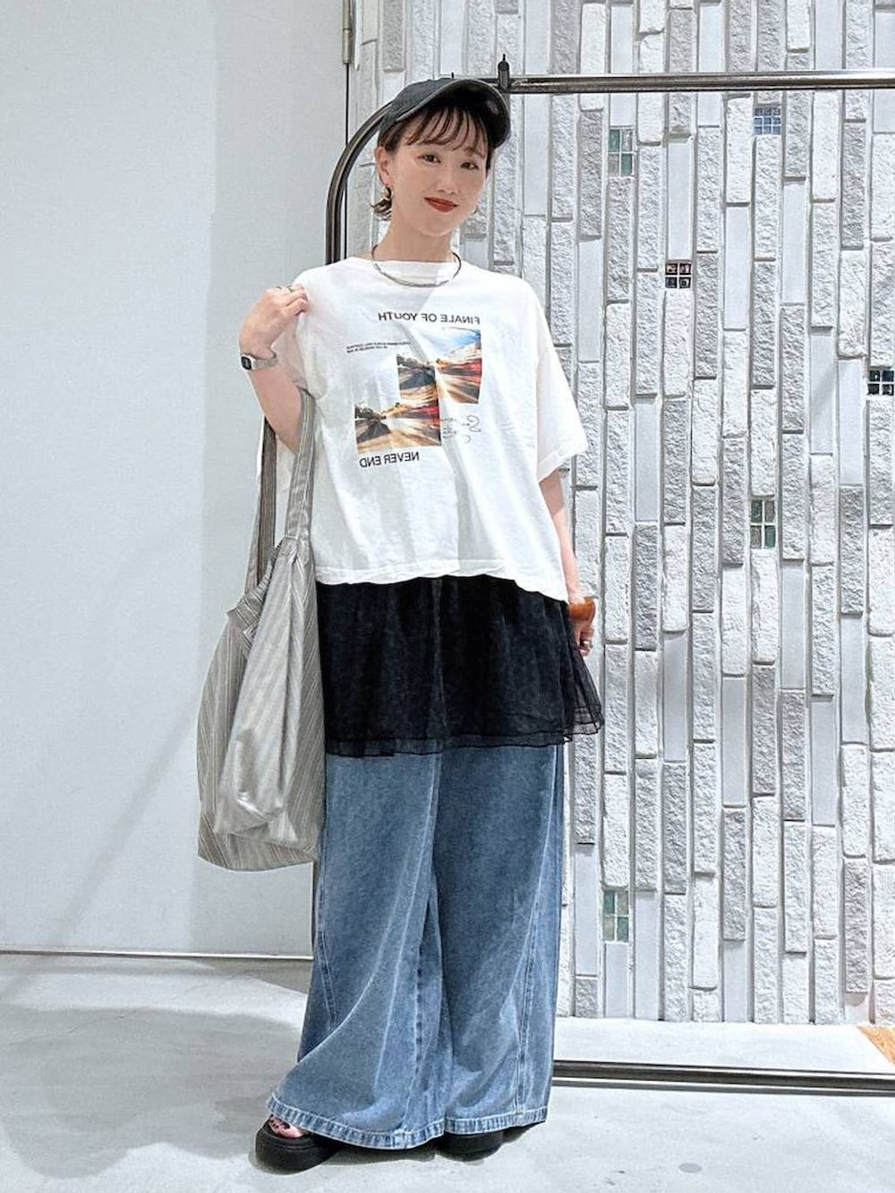 グレー系のトートバッグ、ホワイト系のTシャツ/カットソー、その他のサンダルを着用したレディースの夏コーディネートの2枚目の写真