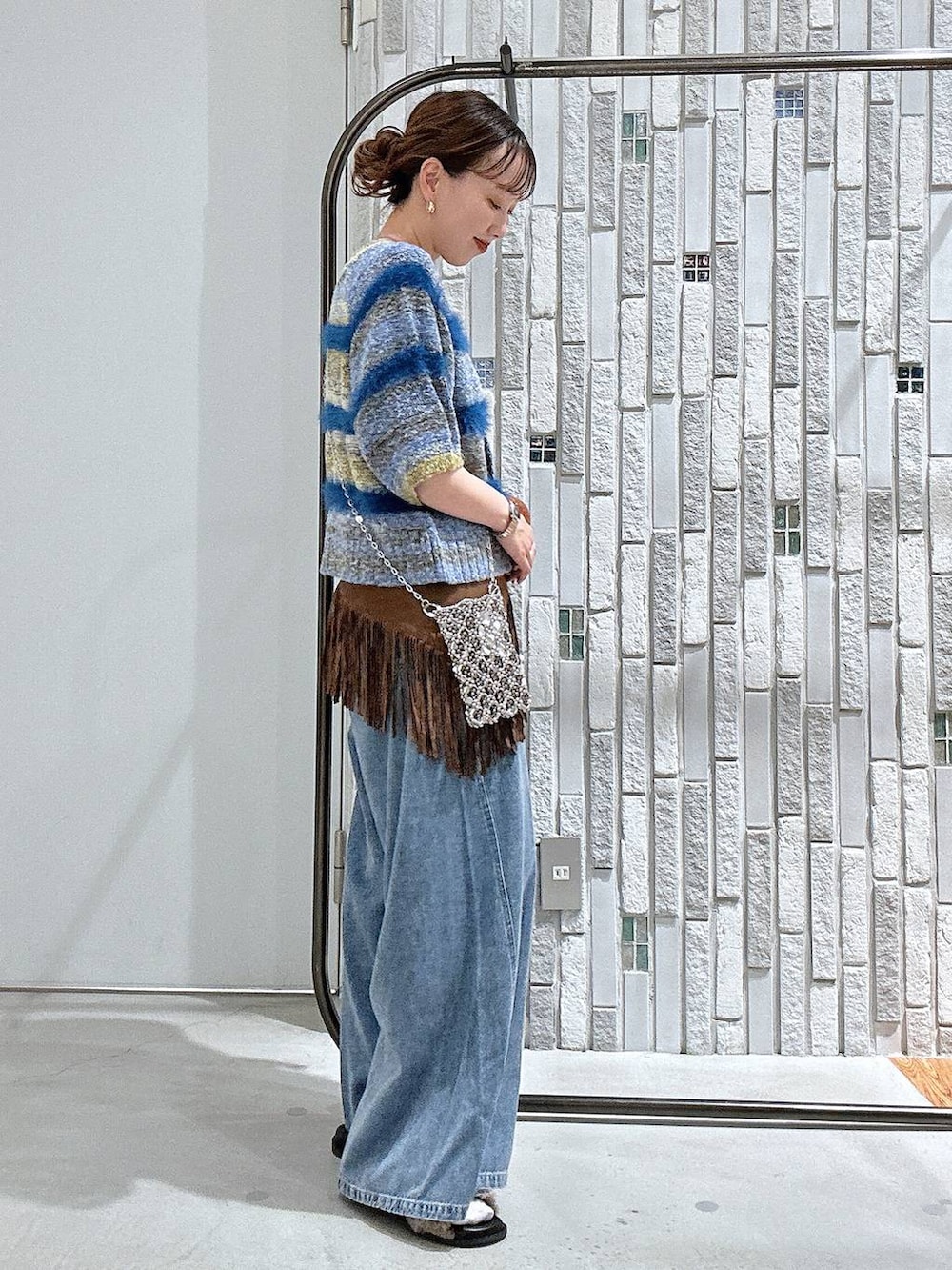 ブルー系のニット/セーター、ブラウン系のサンダル、ブルー系のデニムパンツを着用したレディースの夏コーディネートの3枚目の写真