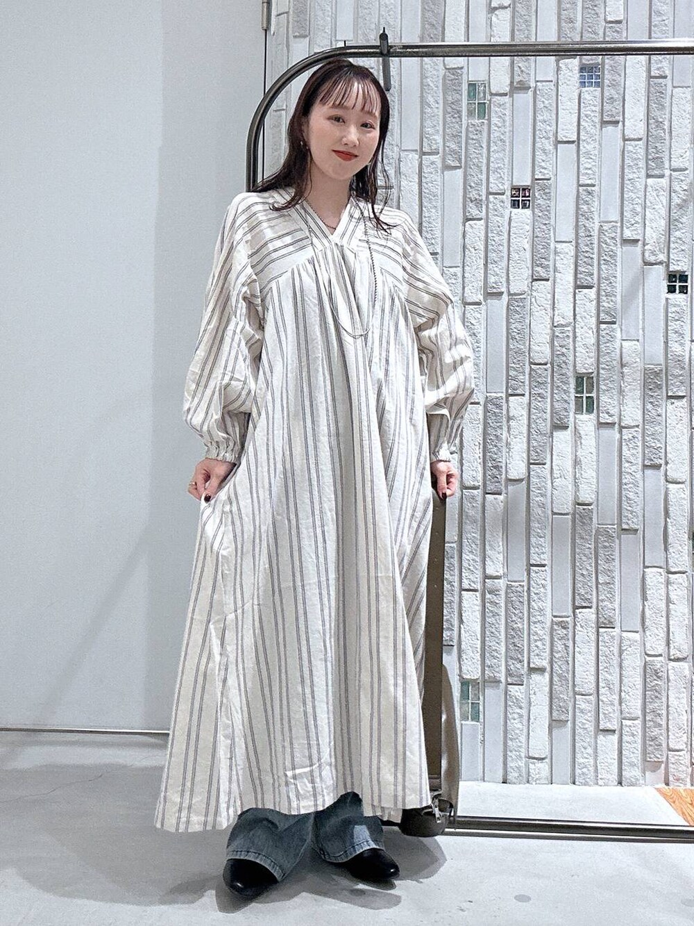 ブラウン系のショルダーバッグ、ホワイト系のワンピース、ブルー系のデニムパンツを着用したレディースの春コーディネートの2枚目の写真