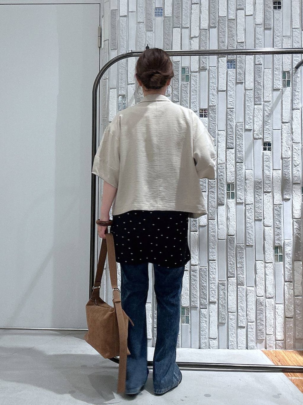 ブラウン系のショルダーバッグ、ブルー系のデニムパンツ、ベージュ系のテーラードジャケットを着用したレディースの春コーディネートの4枚目の写真