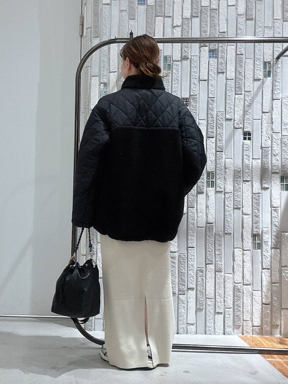 ブラック系のショルダーバッグ、ホワイト系のスカート、ブラック系のブルゾンを着用したレディースの冬コーディネートの4枚目の写真