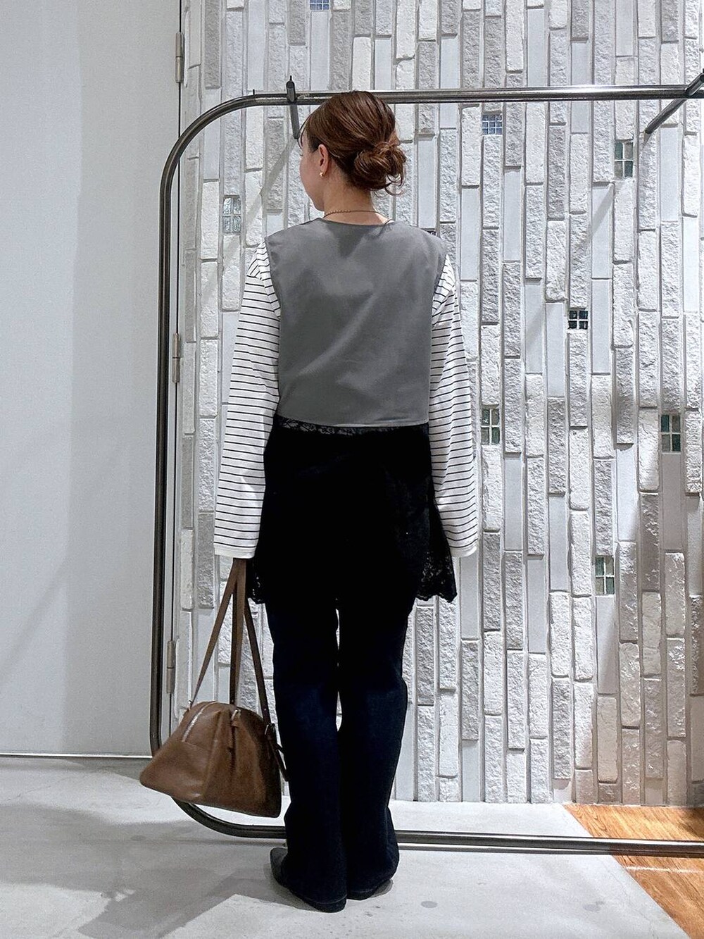 ブラウン系のボストンバッグ、ホワイト系のTシャツ/カットソー、ブルー系のデニムパンツを着用したレディースの冬コーディネートの3枚目の写真