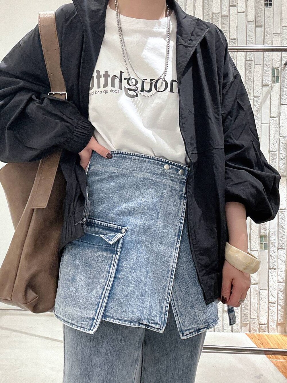 ブラック系のサンダル、ブラック系のブルゾン、ブルー系のデニムパンツを着用したレディースの春コーディネートの5枚目の写真