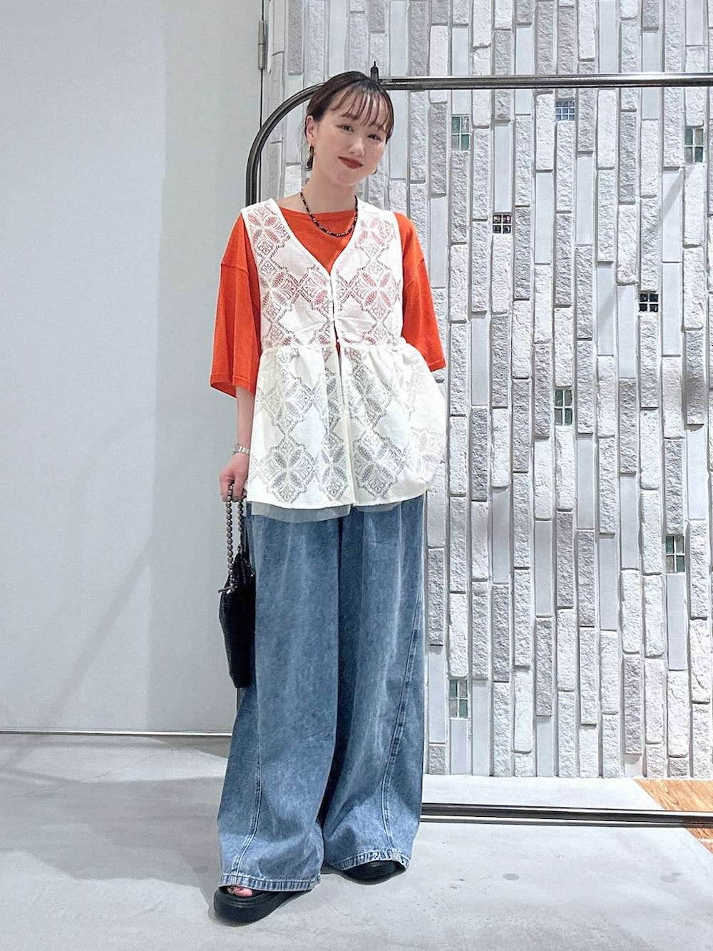 ブルー系のデニムパンツ、ブラック系のサンダル、ブラック系のショルダーバッグを着用したレディースの春コーディネートの3枚目の写真