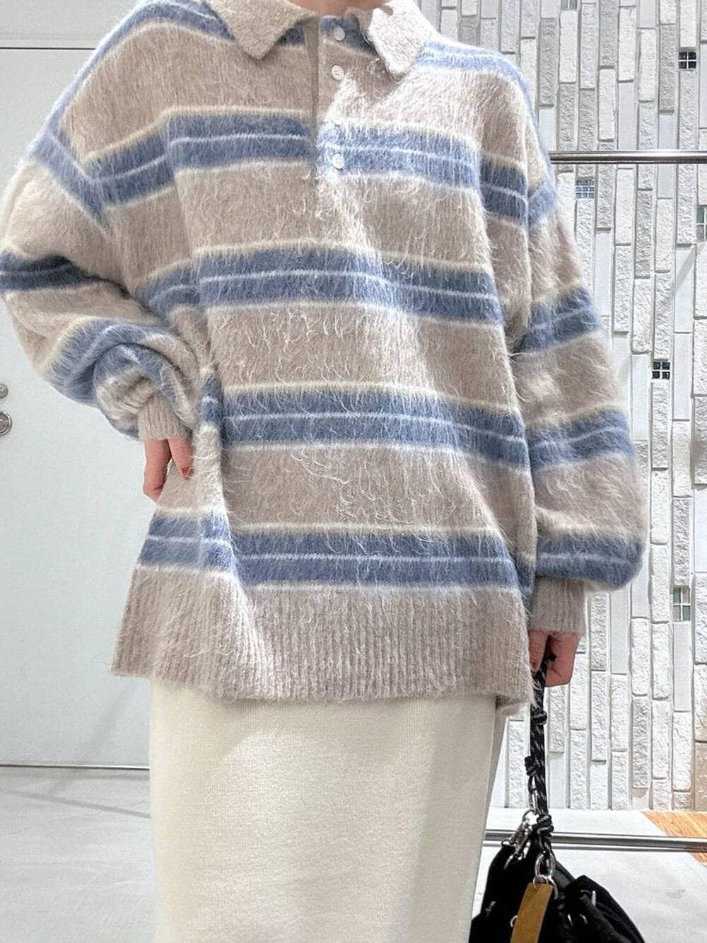 ブラック系のショルダーバッグ、ホワイト系のスカート、ブラック系のブルゾンを着用したレディースの冬コーディネートの7枚目の写真