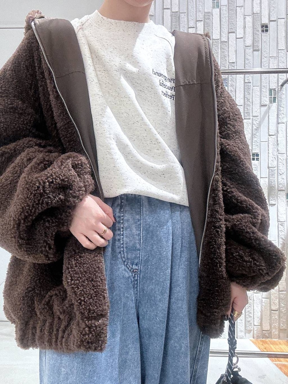 ブラック系のショルダーバッグ、ブルー系のデニムパンツ、ブラウン系のブルゾンを着用したレディースの冬コーディネートの5枚目の写真