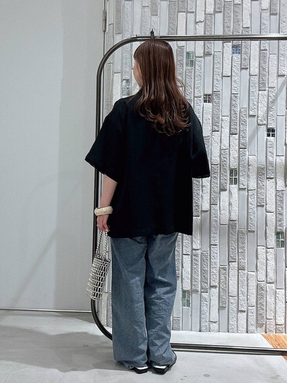 ブルー系のデニムパンツ、ブラック系のテーラードジャケット、シルバー系のショルダーバッグを着用したレディースの春コーディネートの4枚目の写真