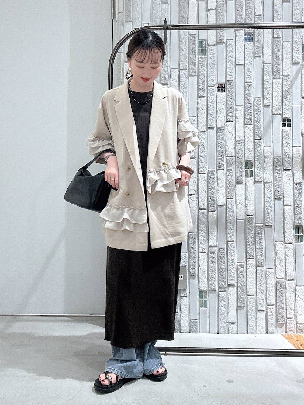 ブルー系のデニムパンツ、ブラック系のサンダル、ブラック系のショルダーバッグを着用したレディースの春コーディネートの3枚目の写真